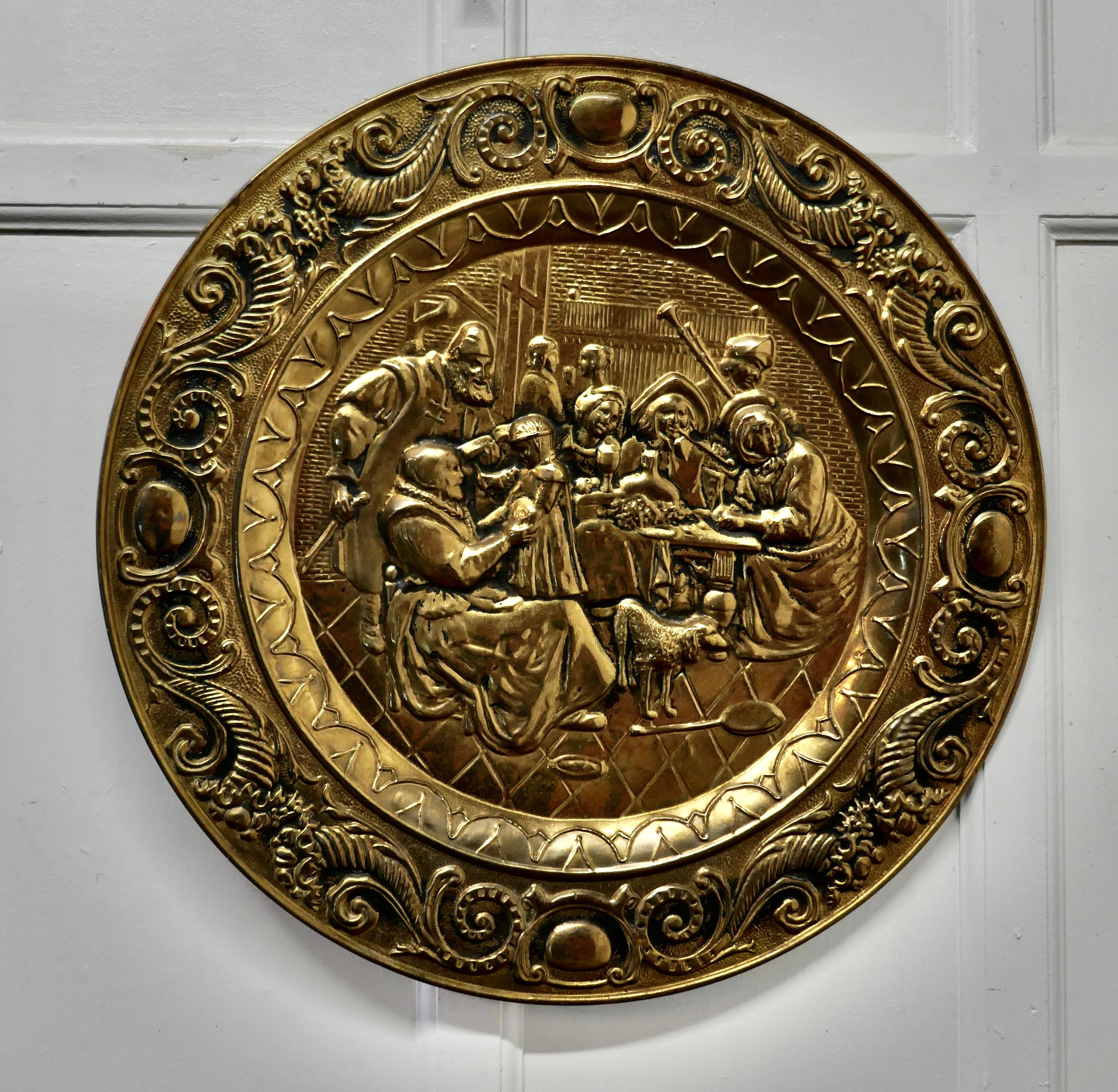 Large Arts & Crafts embossed brass wall hanging charger

This is a large decorative wall piece the charger is made in beaten brass and has a merry tavern scene in the centre and an elaborate 4” wide border
A good looking piece of traditional pub