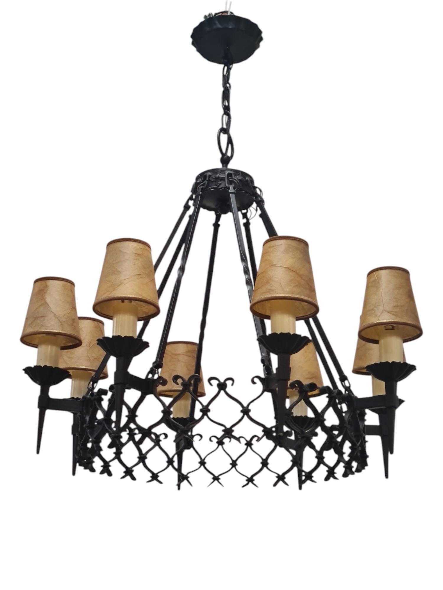 A large Finnish forged wrought iron lamp with beautiful betails. The lamp measures 75cm in diameter with the shades, and features 8 lights protruding from a central ring with an intricate mesh design. The lamp is painted in black and has most