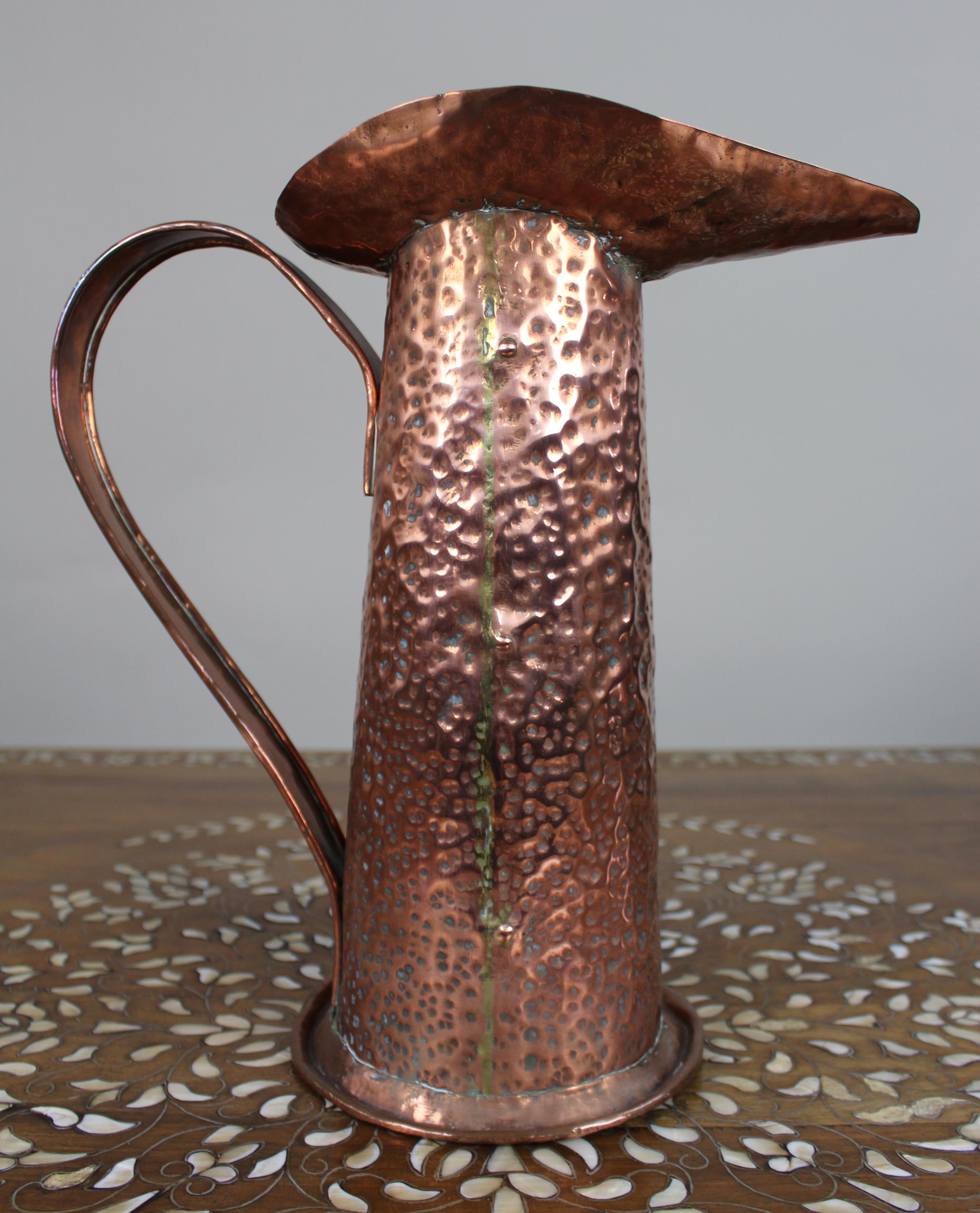 Grande brocca in rame martellato Arts & Crafts, 1900 ca.

Un'impressionante brocca in rame del periodo Arts & Craft dalla forma alta e affusolata con un audace beccuccio svasato e un ampio manico rivettato. La superficie martellata a mano conferisce