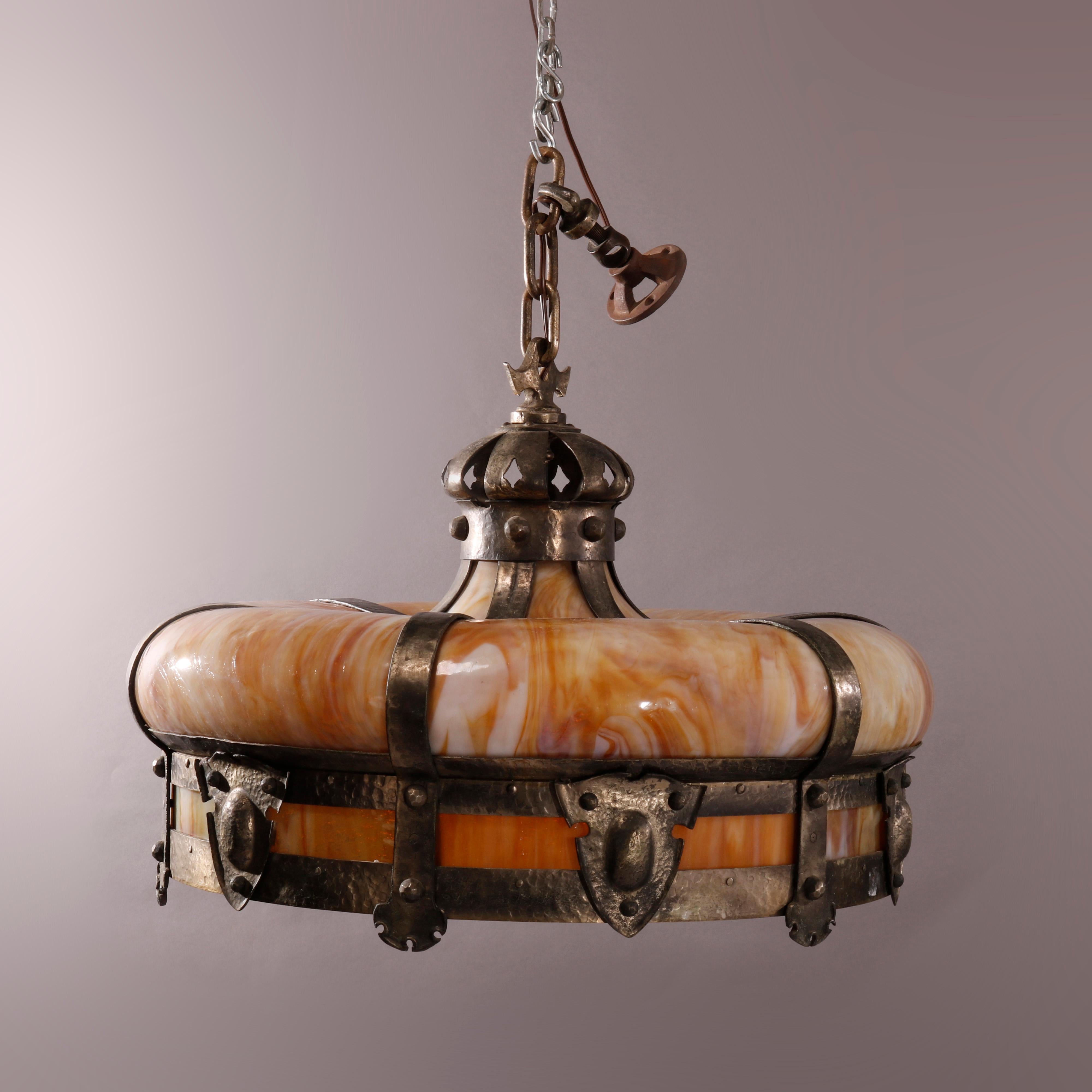 Une ancienne suspension Arts and Crafts à quatre lampes offre une forme de couronne avec du verre de scorie courbé et des bretelles en métal martelé ayant des réserves en forme de bouclier, vers 1920

Mesures - 30'' H x 27'' L x 27'' P.