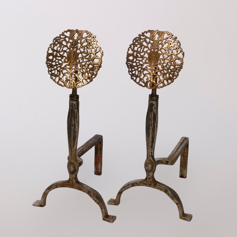 An antique pair of oversized Arts and Crafts fireplace andirons in the manner of Oscar Bach offer reticulated brass stylized sunflower finials over wrought iron bases, c1910

Measures - 27.5''H x 13.25''W x 15.5''D.

Catalogue Note: Ask about