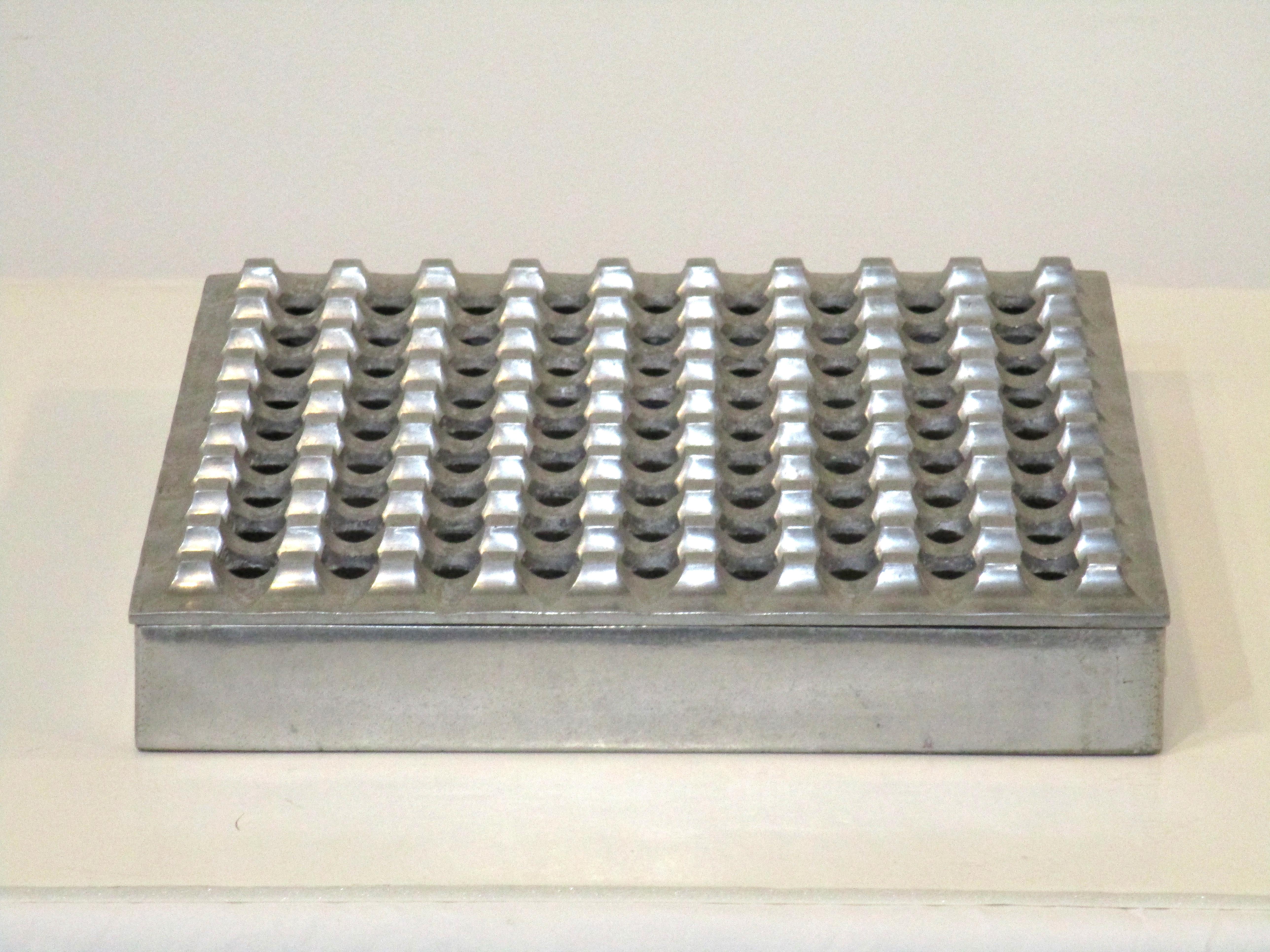 A large sized two piece cast aluminum ash tray or center piece flower tray with 81 holes to the top removeable lid. Designed by Bo Ljungberg and Holger Backstrom for Pascia A.B. Lund Sweden and still retains the original label and sales tag from