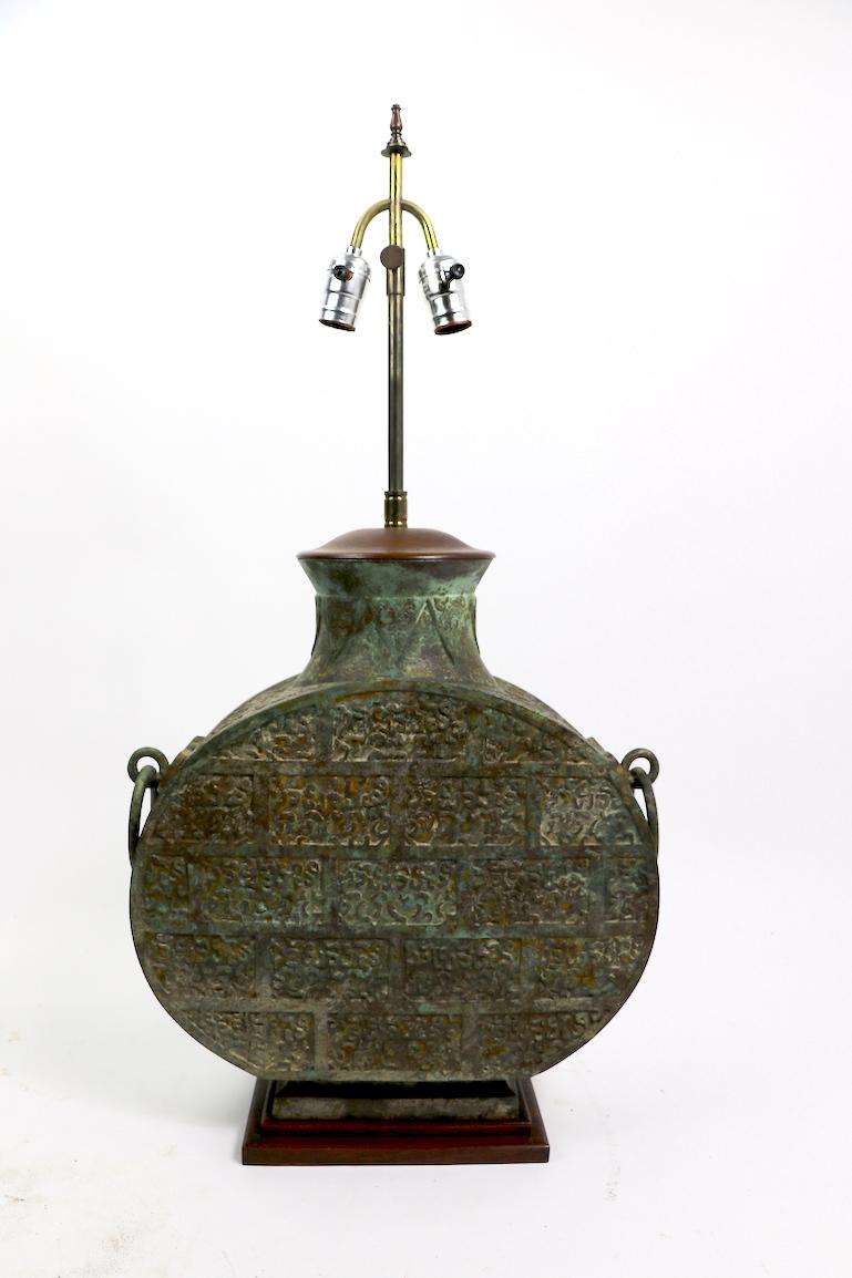 Extraordinary large disk form Archaic Chinese style verdigris bronze table lamp, mounted on a solid wood base with a turned wood top. The brass vertical element is adjustable in height (Extended position 46 H x Lowered position 33.5 H). Lamp body 17