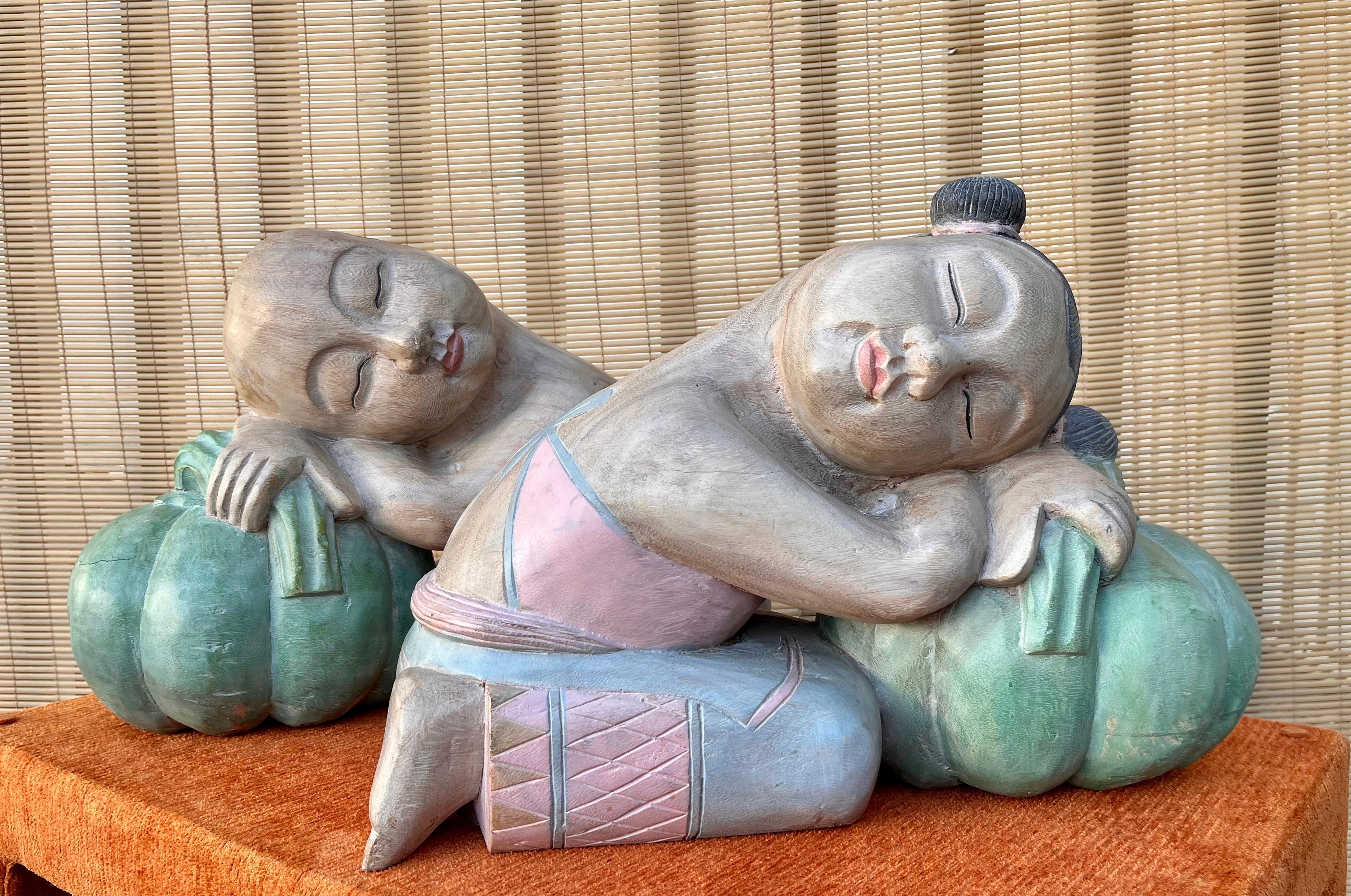 Sculptures décoratives asiatiques en bois sculpté de grande taille, datant de la fin du 20e siècle, représentant des enfants porte-bonheur dormant sur des melons. 
Les figurines d'une fille et d'un garçon dormant, peintes à la main, sont sculptées à