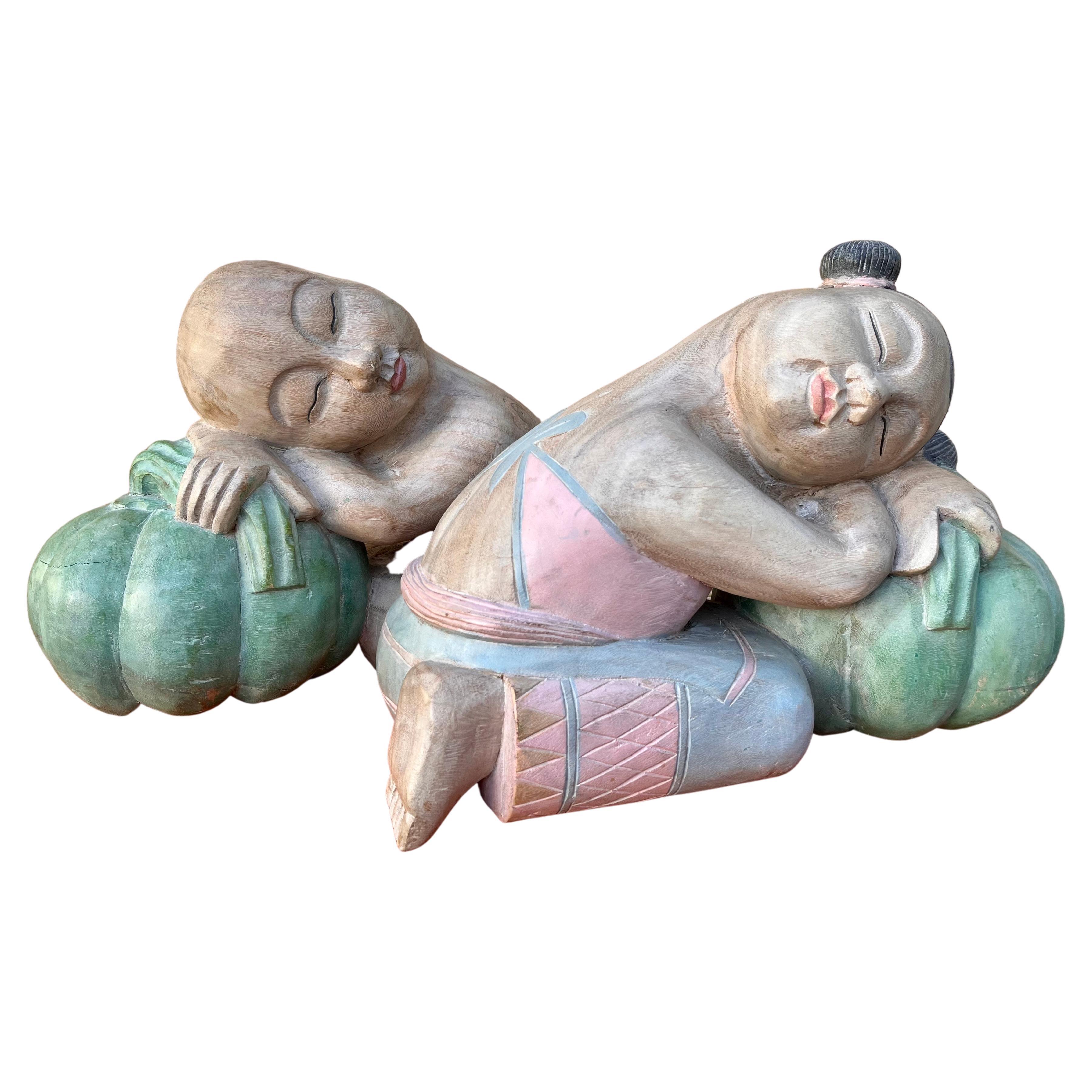 Grandes sculptures asiatiques en bois sculpté représentant des enfants de bonne chance endormis sur des melons