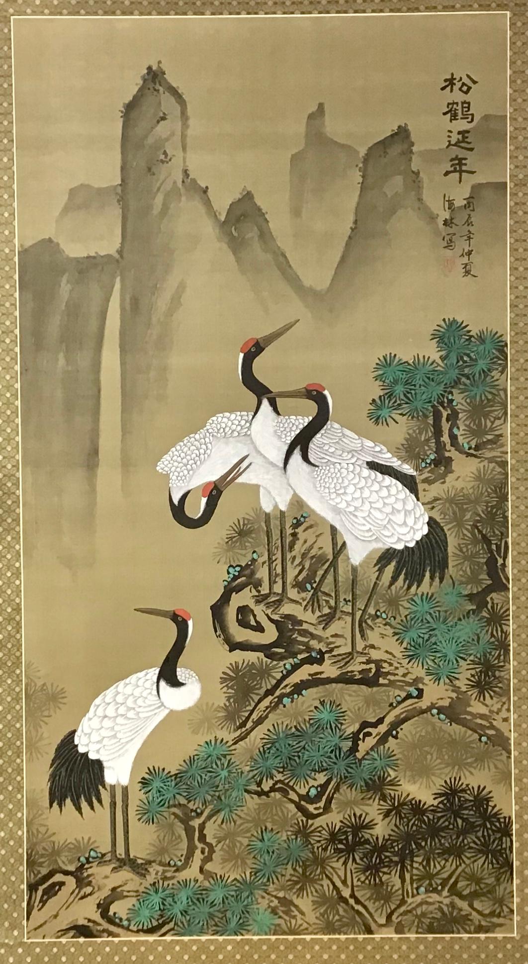 A striking large painting on silk mounted on board of four colorfully painted cranes set against a naturalistic background of mountains and foliage. Black Chinese characters vertically painted on the upper right. Lacquered frame with corners carved