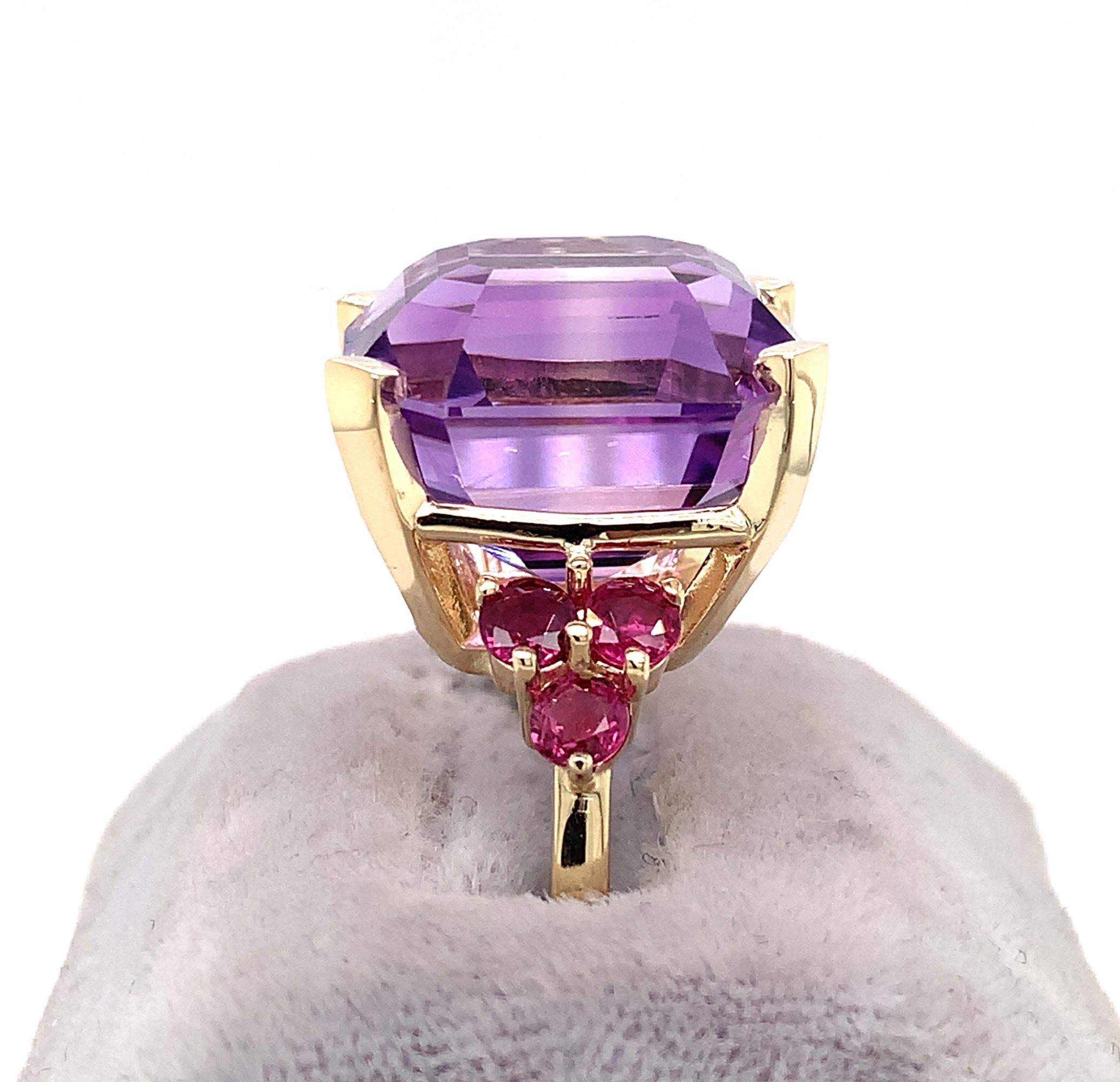 14K yellow gold amethyst and ruby ring featuring a huge asscher cut amethyst. The amethyst is a medium purple color, weighs 20.42 carats and measures about 16.8mm x 15.2mm. There are 6 round ruby accents, each measuring about 3.5mm. The ring fits a