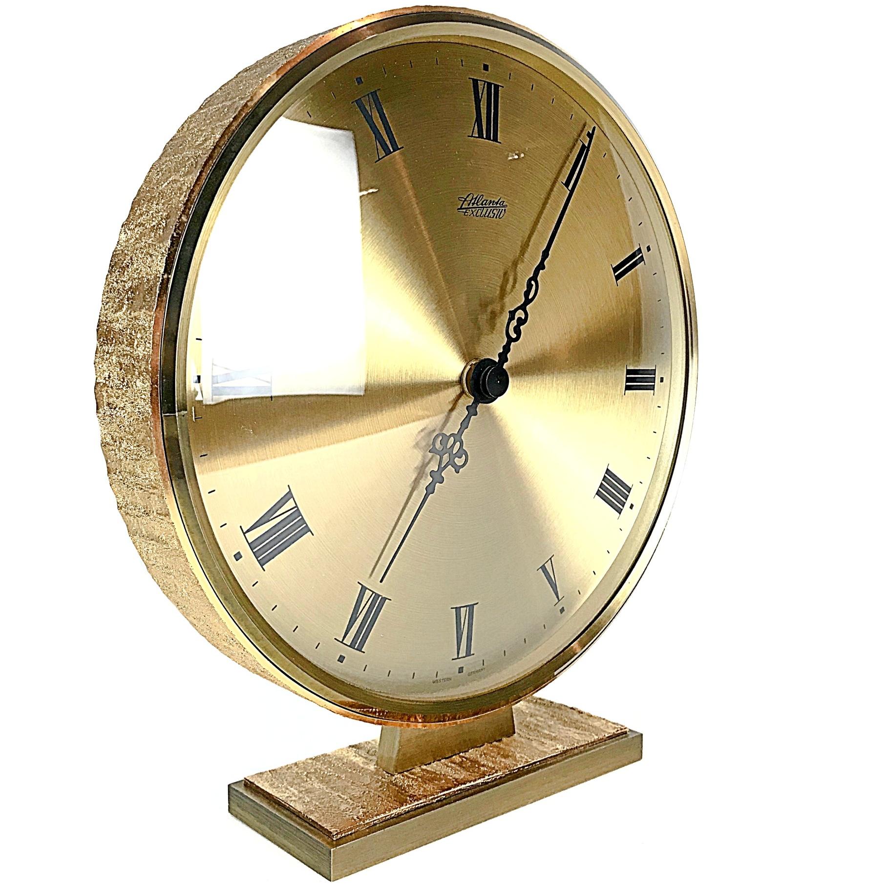 Impressive unique table clock made by Atlanta, West Germany in 1950s. Heavy slim-line brass body with glass front. Great condition with original Junghans quartz AAA battery mechanism.

Measures: 
Height 26 cm / 10.2 in. 
Diameter 24 cm / 9.8
