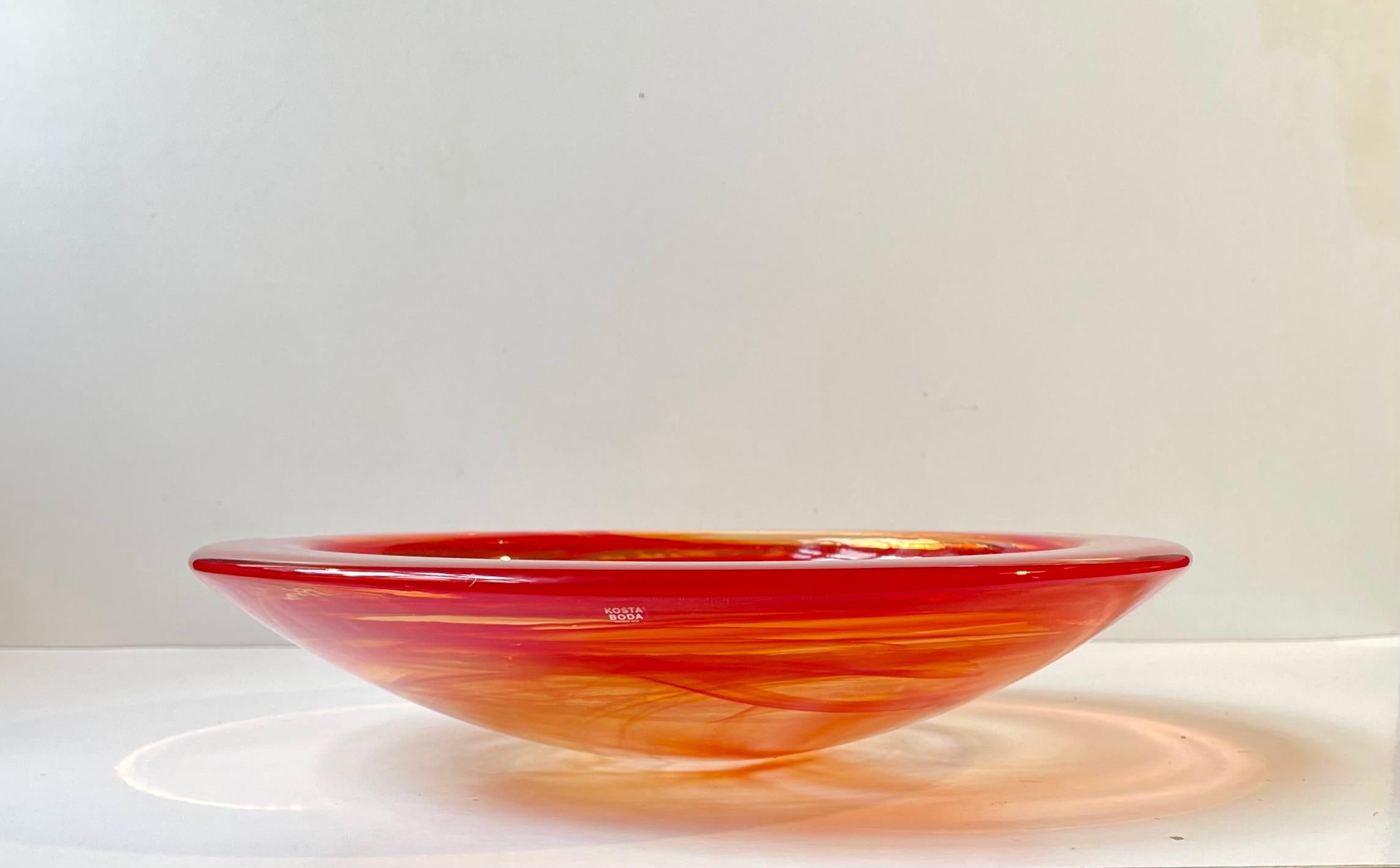 Thick, heavy centerpiece bowl in red/orange/clear glass from Kosta Boda in Sweden. It was designed by Anna Ehrner in the mid 1980s. The bowl is called Atoll or lava and it features swirl-work to the inside of the bowl. Original sticker from Kosta