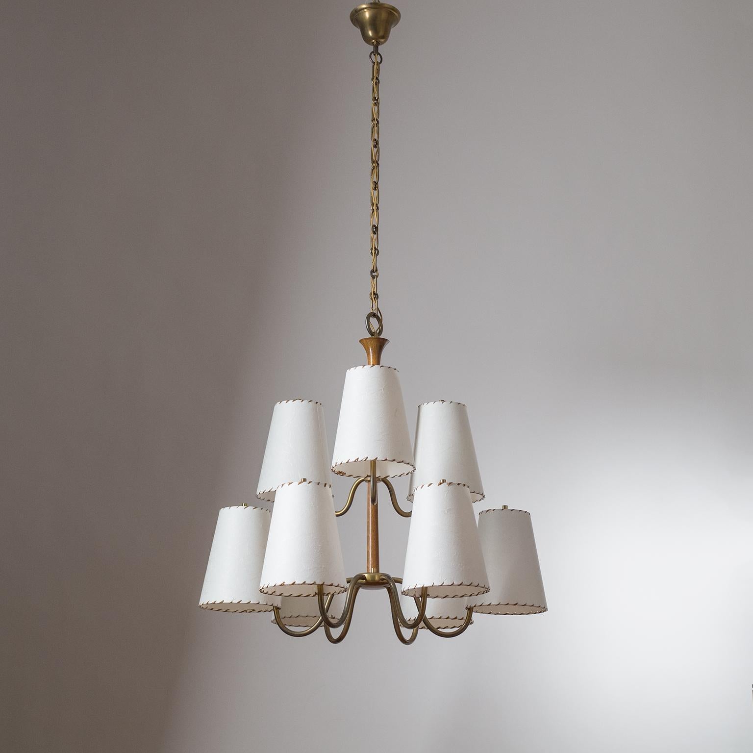 Rare large Austrian nine-arm chandelier from the 1930s, attributed to J.T. Kalmar, featuring brushed brass hardware with a rare stained hardwood stem. Arranged in two tiers are nine large paper shades with raffia 'stiching', each housing an original