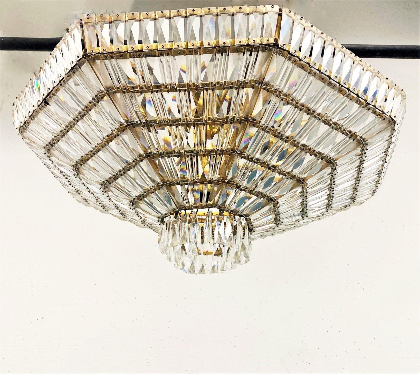 A large, glamorous Hollywood-Regency style nine-light flush mount or ceiling light, Austra, 1960s. Handcrafted of Swarovski crystals and brass forming a diamond shape, six fixed tiers with handcut faceted crystals and two hanging tiers on the