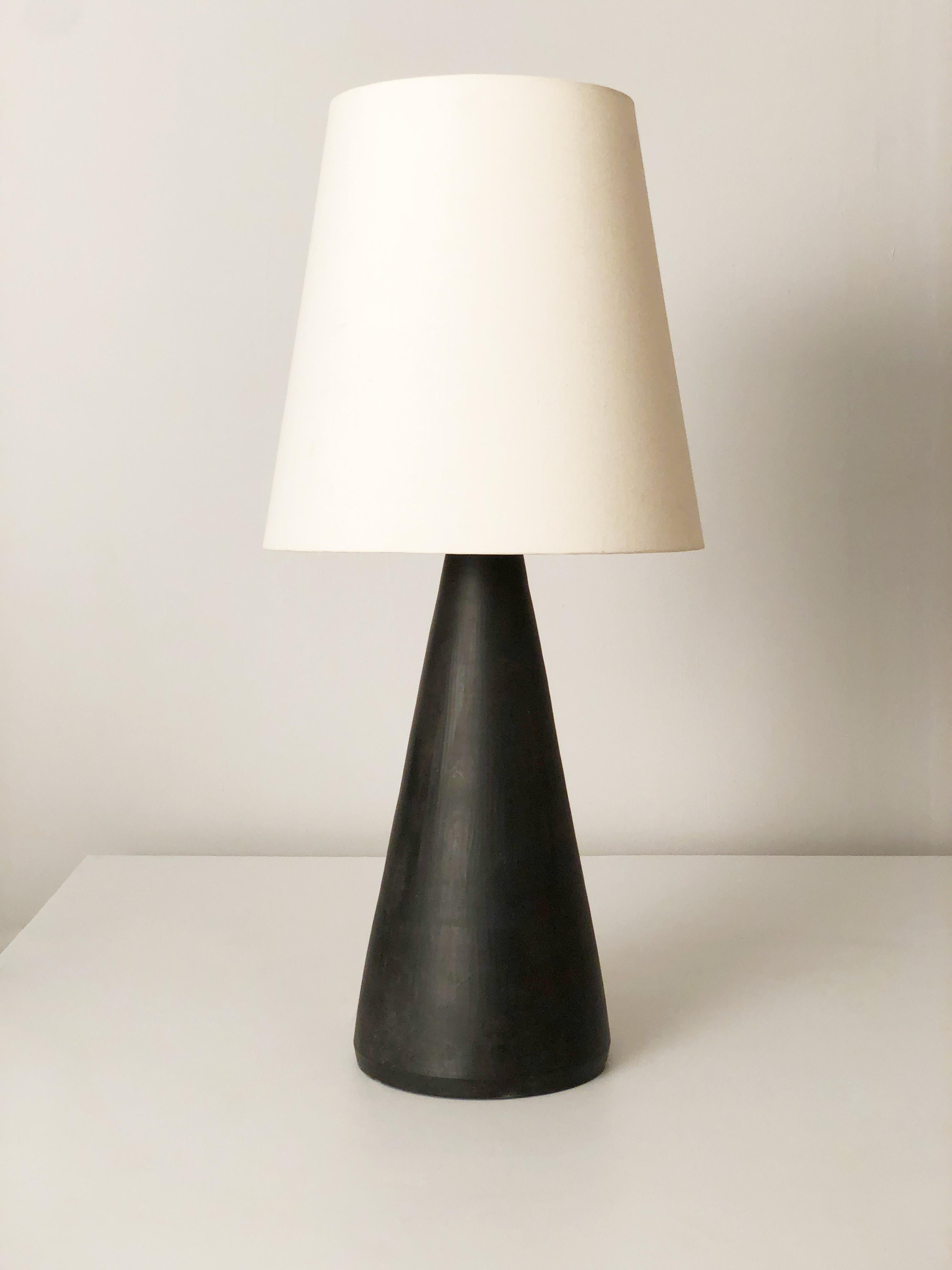 A tall black mat glaze mid-century ceramic table lamp by Danish ceramicist, glass workers and potter Axel Brüel (1900–1977). Later lamp shade in off-white cotton fabric over styrene backing. Axel Brüel was working as a ceramicist for Nymølle between
