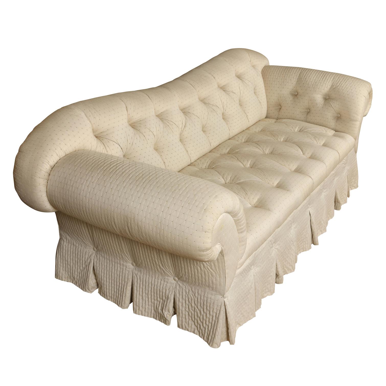 Large Baker tufted upholstered ivory English sofa with shaped back, roll arms and pleated skirt.