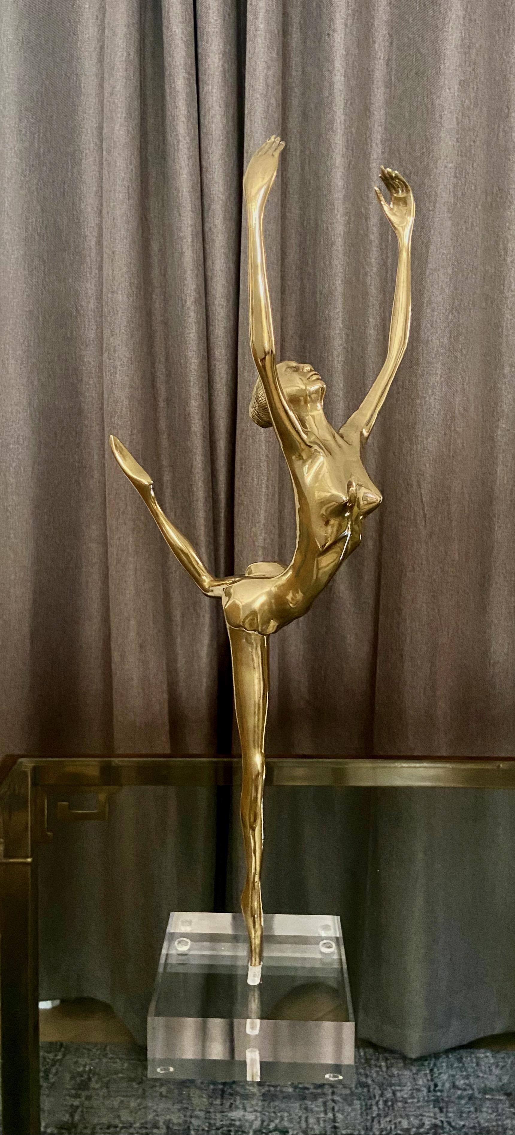 An inspiring and graceful stylized brass ballerina dancer statue mounted on an acrylic stand. Her facial expression and elongated hands and fingers are beautifully detailed. Made during deco era.