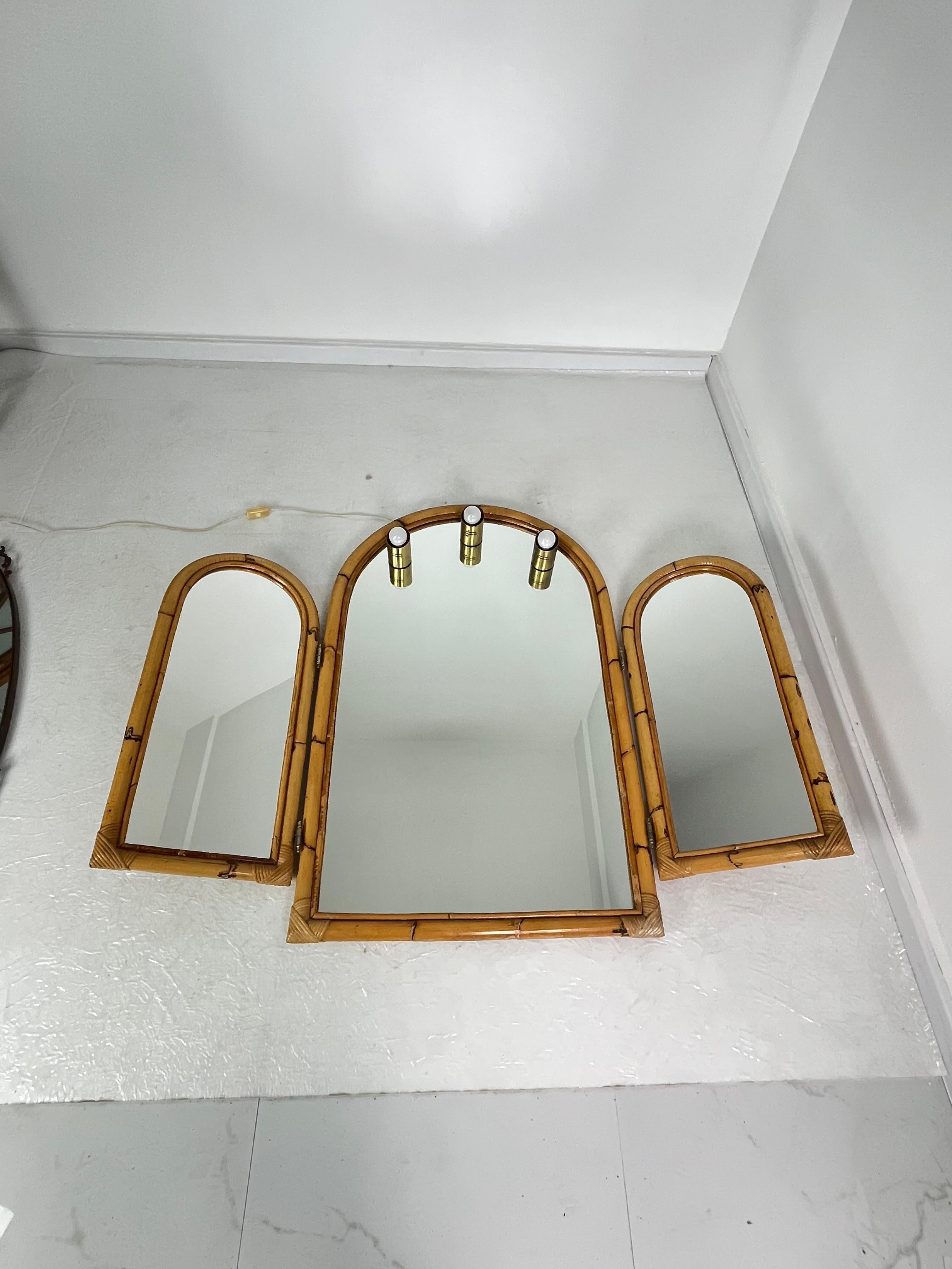 Large bamboo bathroom mirror with adjustable side panels and three lights, 1970s.
Brass details.
With the doors open, it measures 139 cm wide.
Height 110 cm.
Depth 8 cm.
E14 bulbs.
Intact and in good condition.

We guarantee prompt shipping with