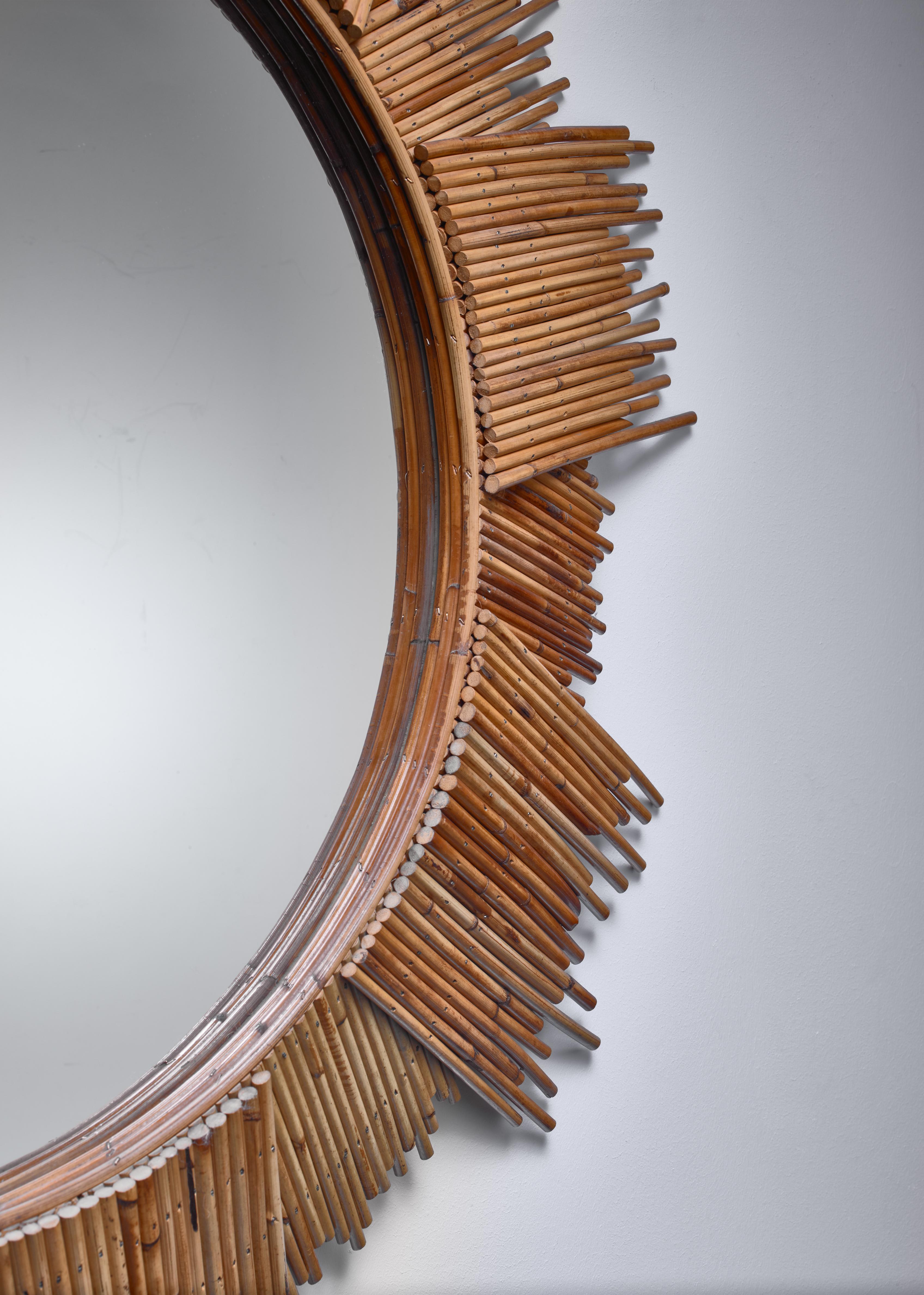 A large (115 cm/45 inch diameter) Mid-Century Modern sunburst wall mirror in a frame made of bamboo pieces of different sizes. Beautiful warm patina.