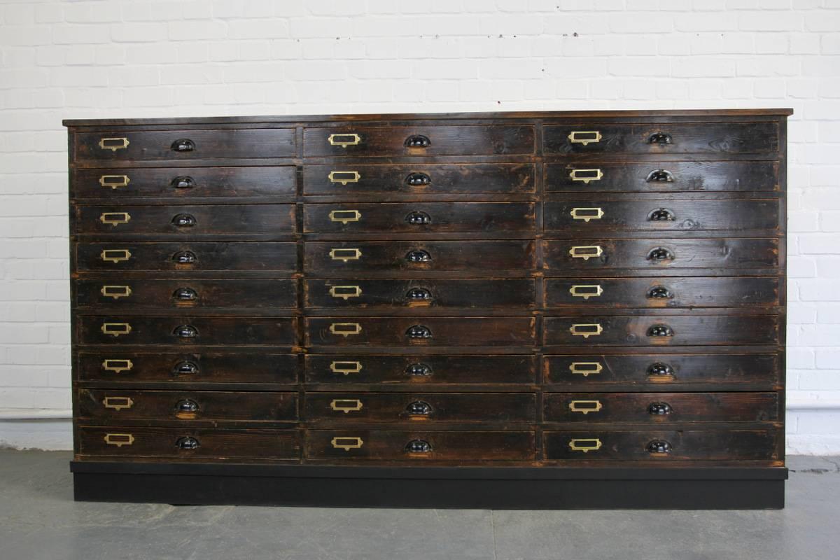 Large bank of industrial drawers, circa 1950s

- Pine drawer fronts and sides
- Brass card holders
- On large castors
- Black aluminum cup handles
- 27 drawers
- Dutch, circa 1950s
- Measures: 207 cm long x 59 cm deep x 112 cm tall
- Each