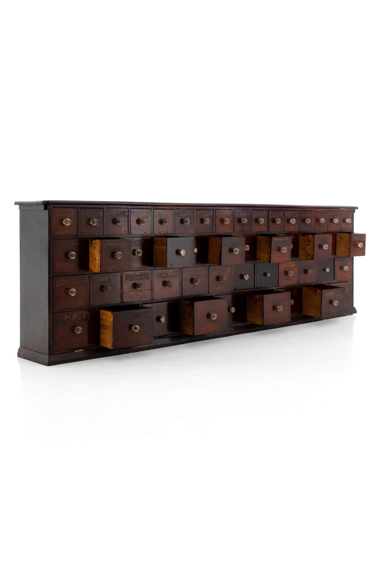 A commanding bank of forty-nine Victorian chemist drawers in mahogany, built by Parnall and Sons of Bristol. Featuring drawers of various sizes with original bevelled glass knobs to each. Sympathetically restored with remnants of original hand