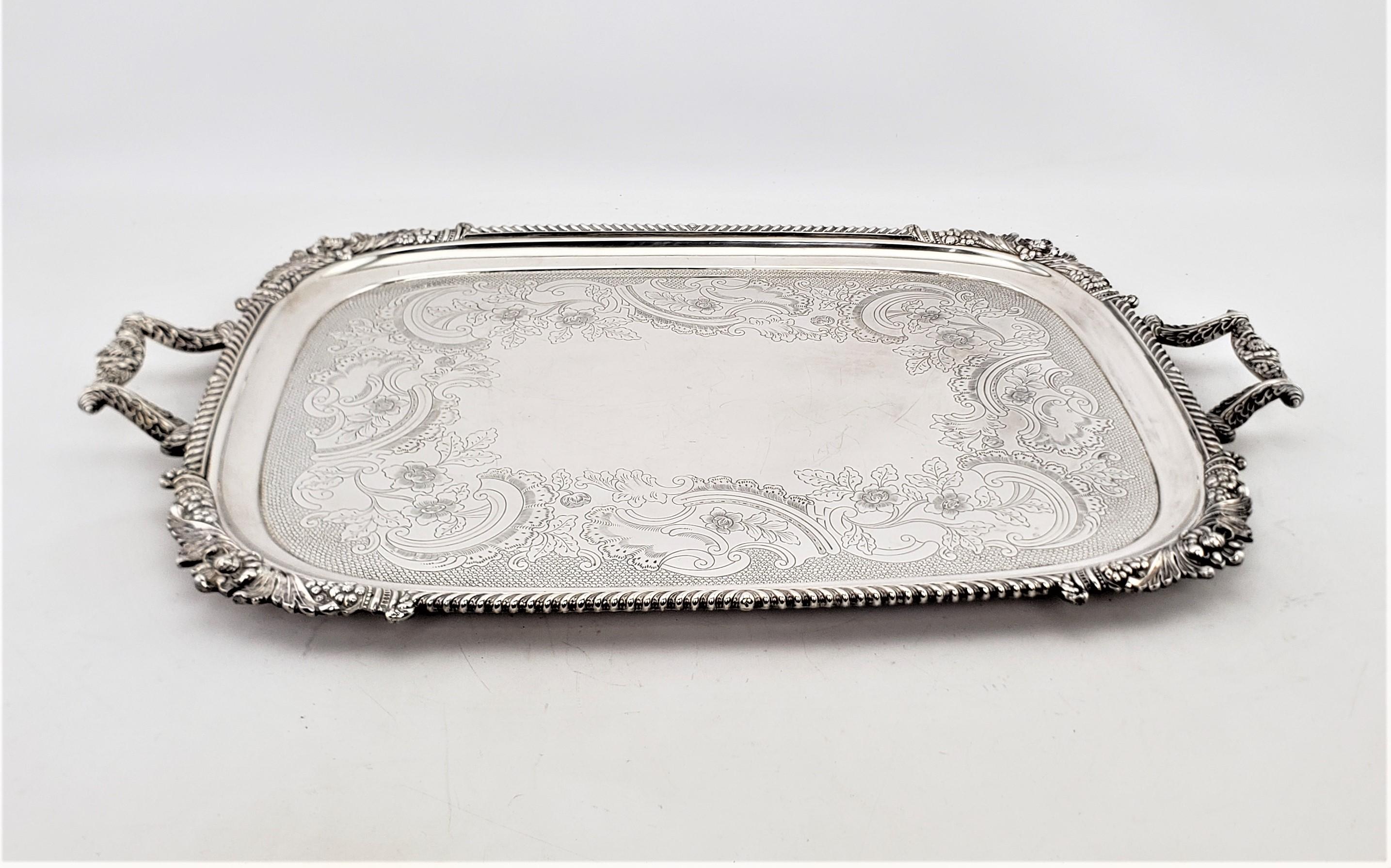 This very large and substantial serving tray was made by the well known Barker-Ellis Silver Co. of England in approximately 1920 in a Victorian style. This rectangular shaped tray is done in silver plate with applied floral decoration around the