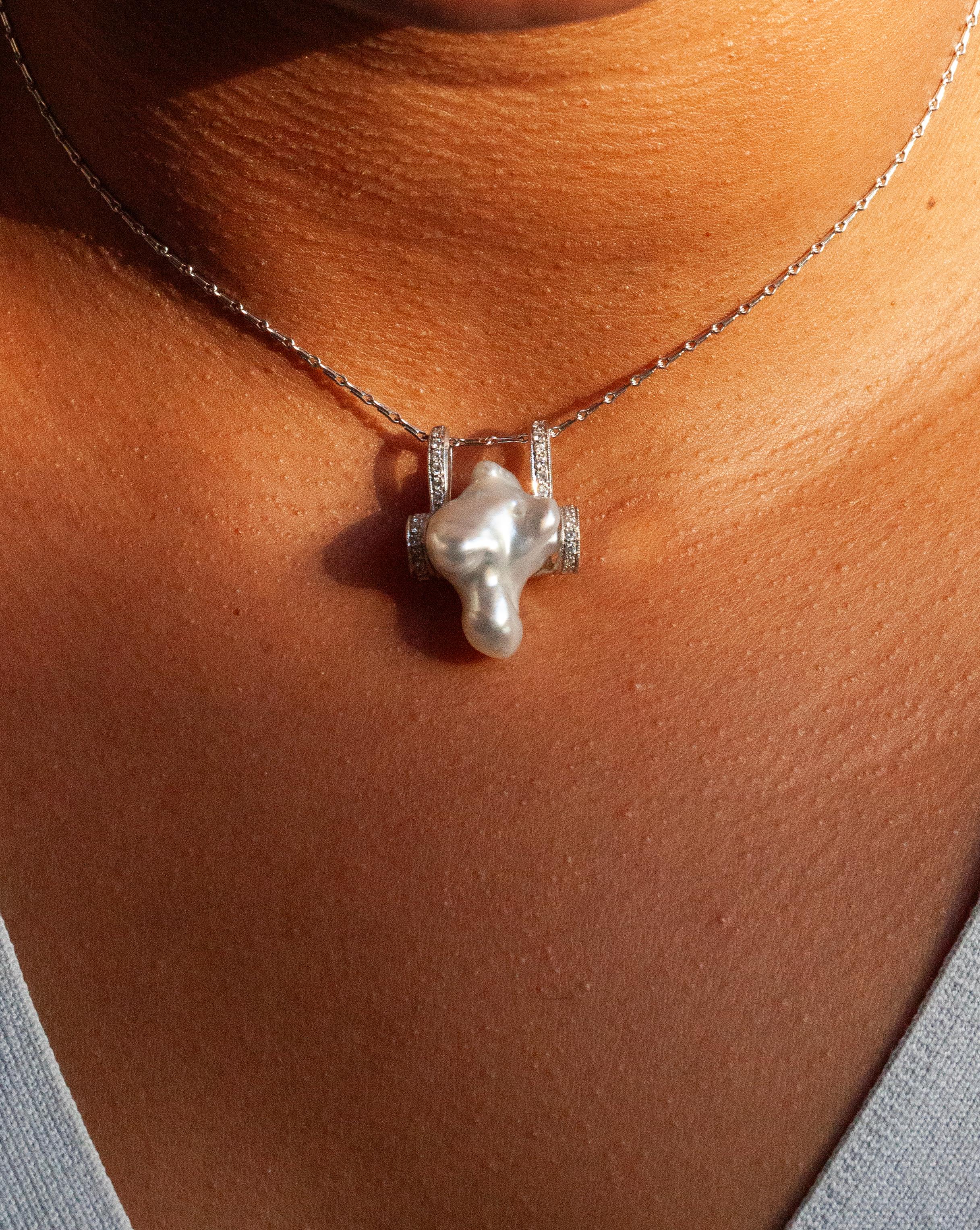 This pearl and diamond pendant necklace is definitely a piece of art that promises to stand out and draw admiration wherever it is worn.

Centring the luxurious piece is an unusual pendant expertly crafted from 18 carat white gold. At the heart of