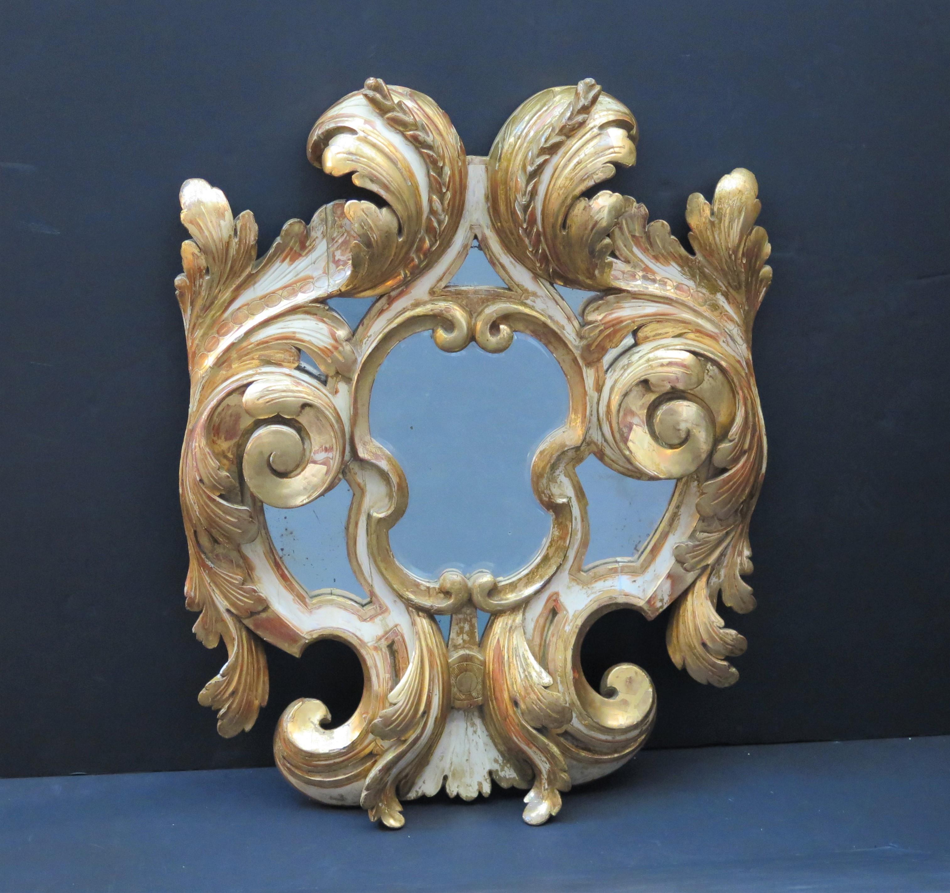 Miroir en bois doré peint et parcellisé de style baroque italien du 19e siècle, de grands feuillages à volutes centrent la plaque de miroir, flanquée de chaque côté de petites plaques de miroir plates.