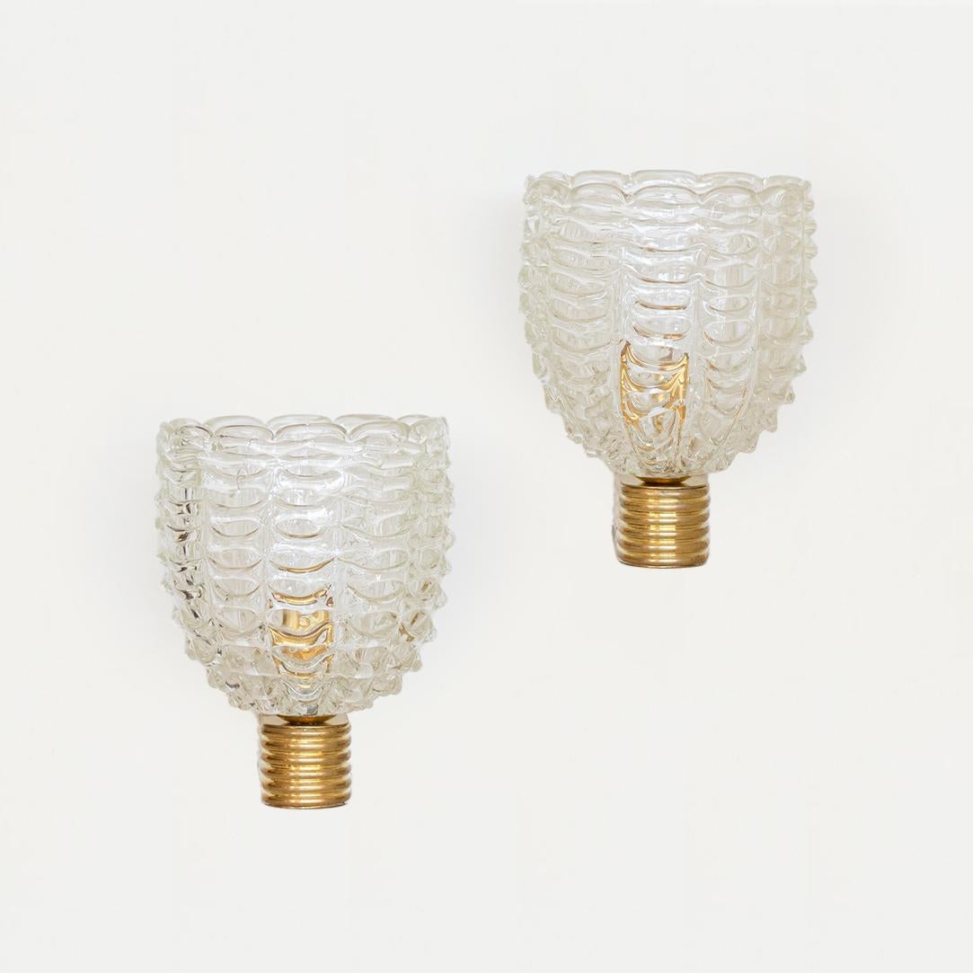 Stunning pair of large Italian glass sconces by Barovier. Clear scalloped ribbed glass shades with single socket. Original ribbed brass arm attaching to wall. Newly wired. Original backplate measures 1.5