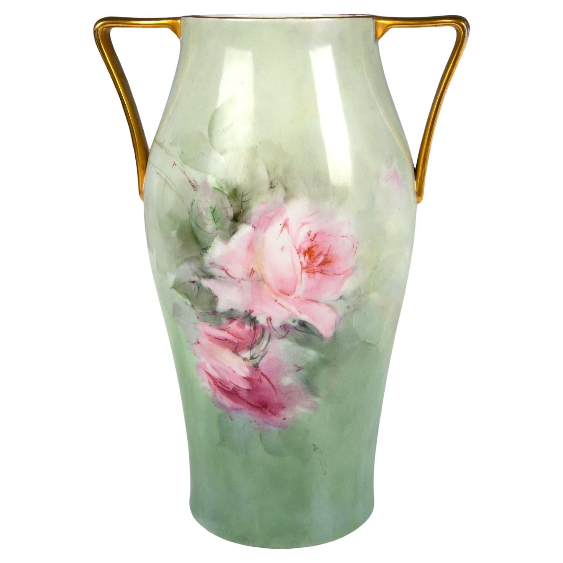 Ti presentiamo uno splendido vaso in porcellana bavarese dell'inizio del XX secolo di H. H. & Co. di Selb, in Baviera. Questo grande vaso a doppio manico vanta squisite rose rosa dipinte a mano su entrambi i lati, catturando la bellezza e l'eleganza