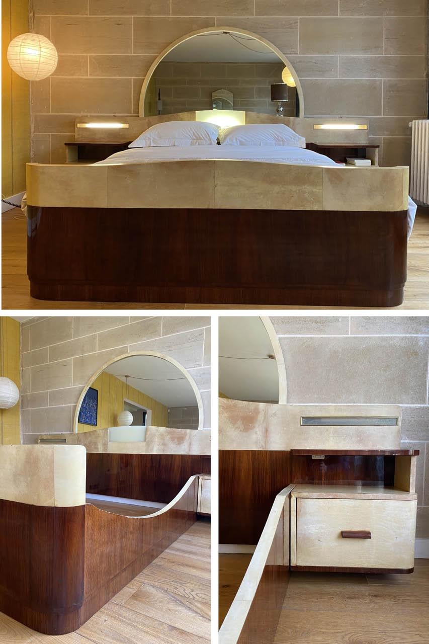 Important Art Deco bed, made of rosewood and parchment veneer, including a headboard integrating the bedside tables, a bed frame and an important semi-circular mirror. It is equipped with two side lamps integrated above the bedside tables and a