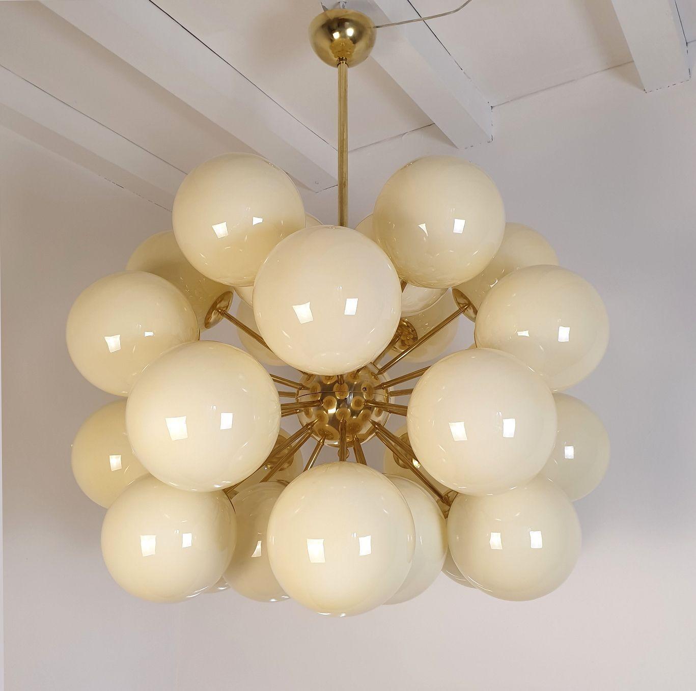 Very large Mid-Century Modern Beige Murano globes Sputnik chandelier, Italy circa 1990s.
The huge chandelier is made of brass mounts and 30 Murano glass globes, each nesting one light.
The glasses are translucent, in a pale amber or beige color.
The