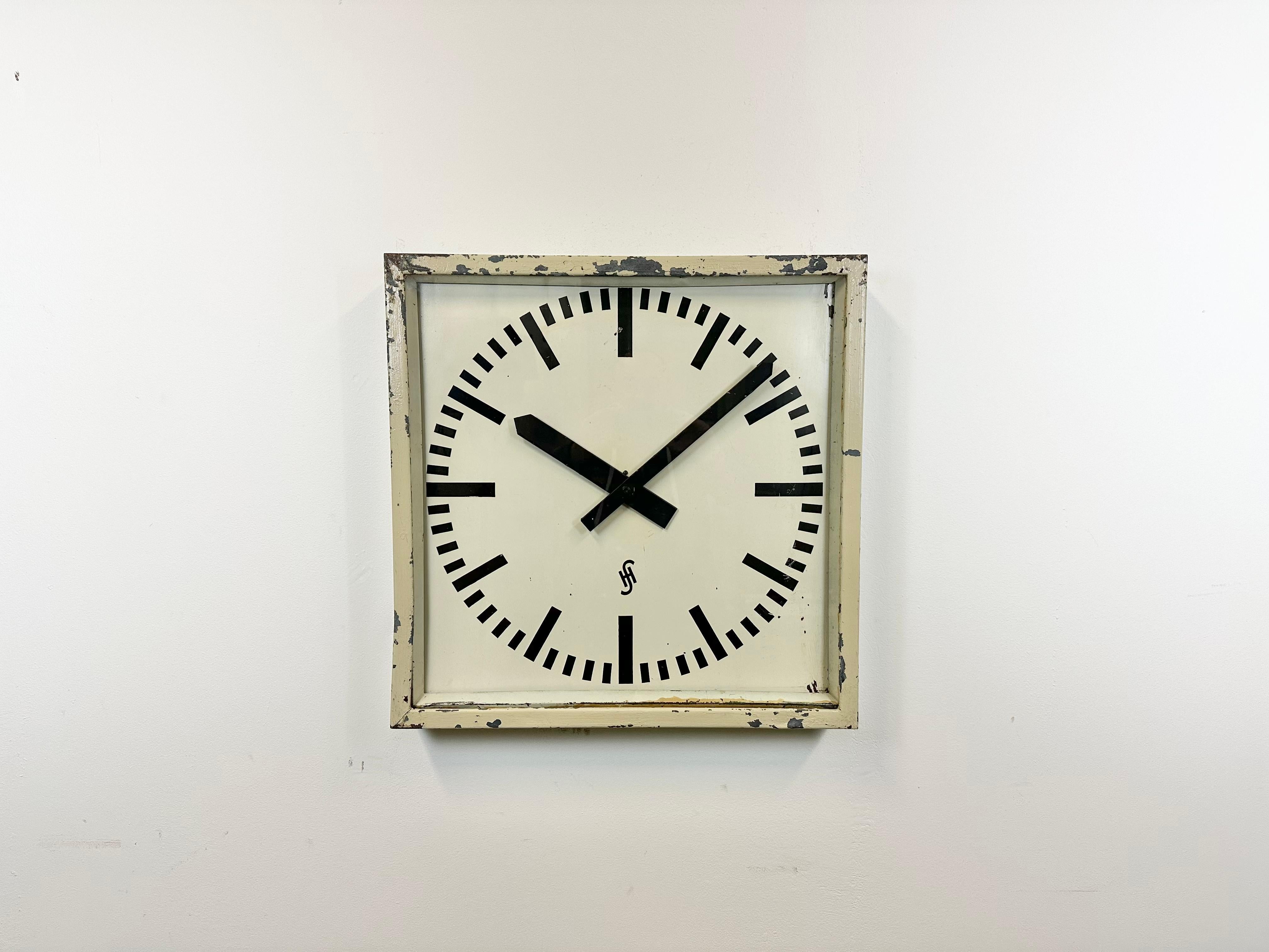 This large wall clock was produced by Siemens and Halske in Germany during the 1950s. It features a beige metal frame, an iron clockface, and a clear glass cover. The piece has been converted into a battery-powered clockwork and requires only one