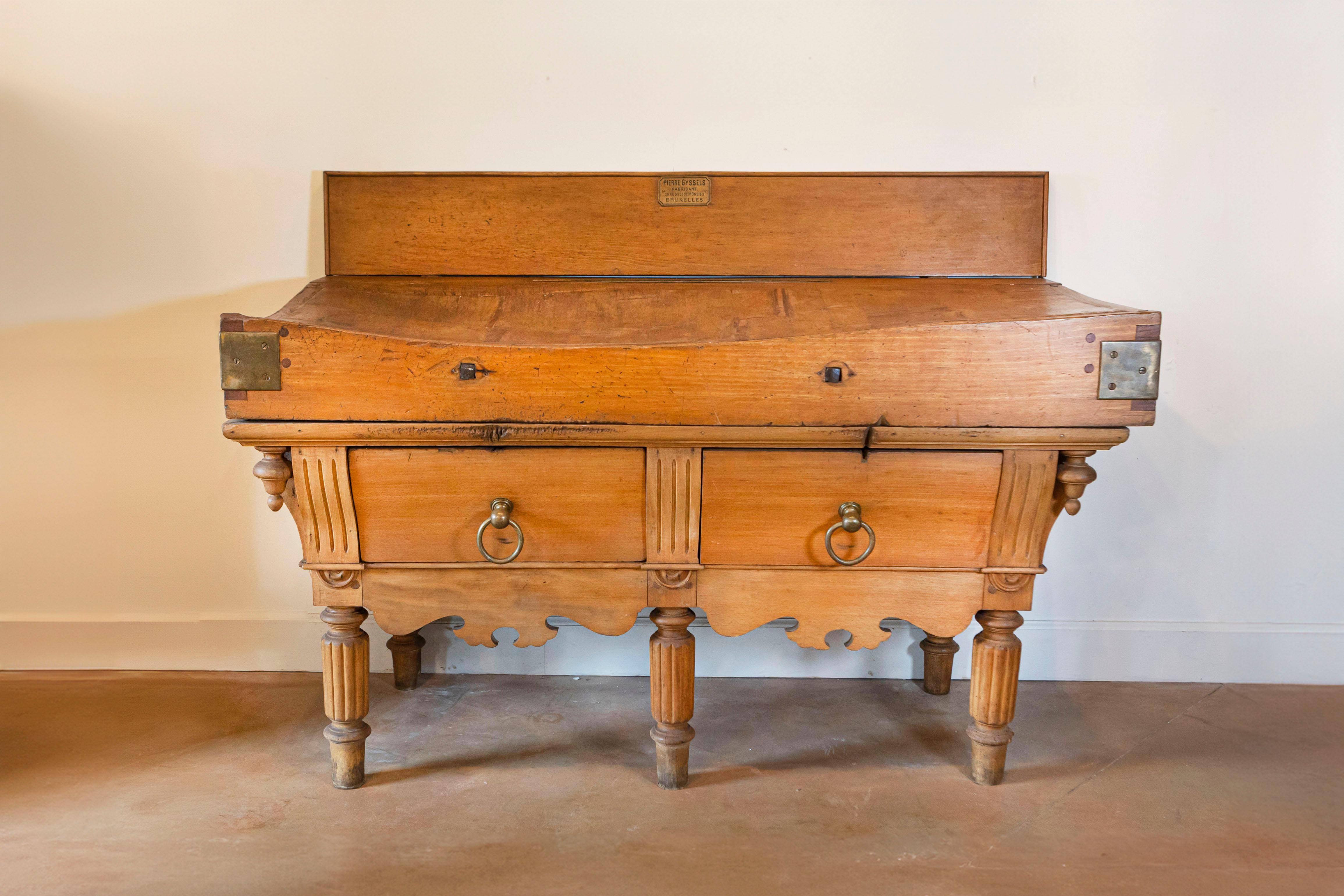 A Belgian large size butcher block table with its maker's plaque, original brass or bronze hardware, two drawers and reeded legs from the late 19th century. This butcher block was born in Brussels during the later years of the 19th century. The