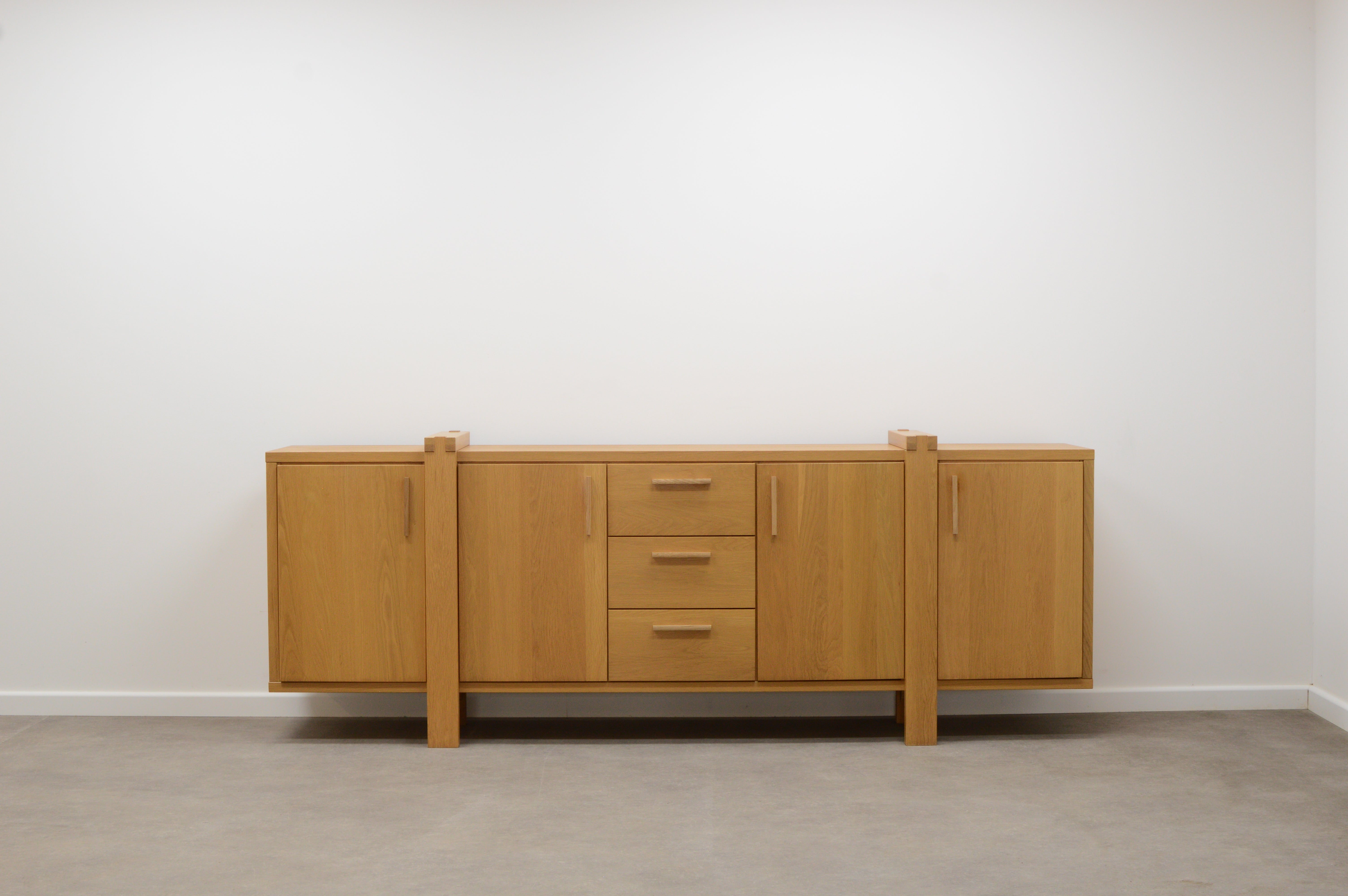 Large Belgium oak sideboard. Mostly made of solid oak. 3 drawers and 4 doors. Behind every door are modular shelfs. In very good vintage condition.
