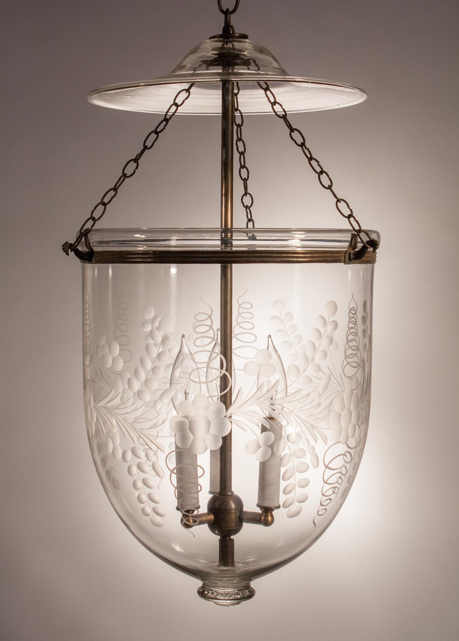 A superb quality hand blown glass bell jar lantern with wonderful form and an etched floral motif. This larger-sized pendant light features its original smoke bell, rolled brass band and suspension chains. It has been newly electrified with a