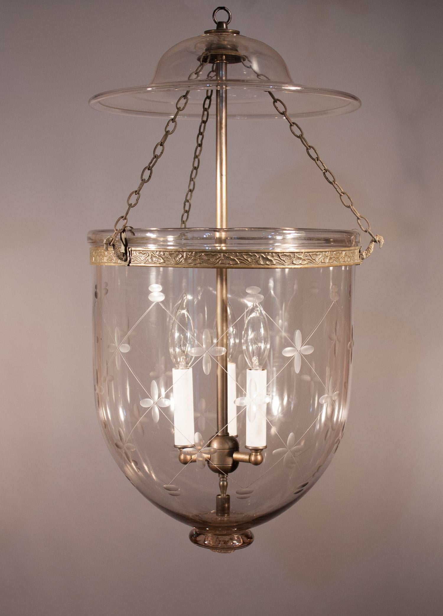 An exceptional quality hand blown glass antique bell jar lantern with its original bell-shaped smoke lid. The pendant's brass band, which has an embossed vine design, has been replaced for safety. The larger size, full form, and character of this