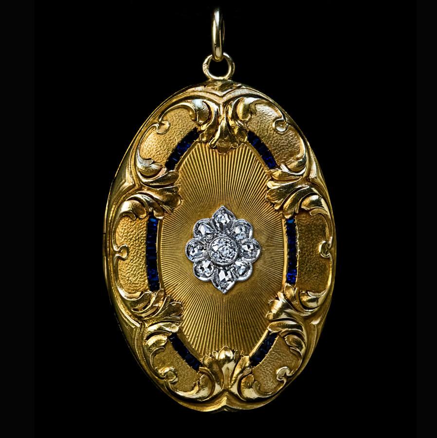 Circa 1900
An antique 18k gold pendant locket centered with a diamond-set platinum rosette and accented by a superbly chased Belle Epoque leaf motif. The rosette is embellished with eight rose cut and one old European cut diamonds. The engraved