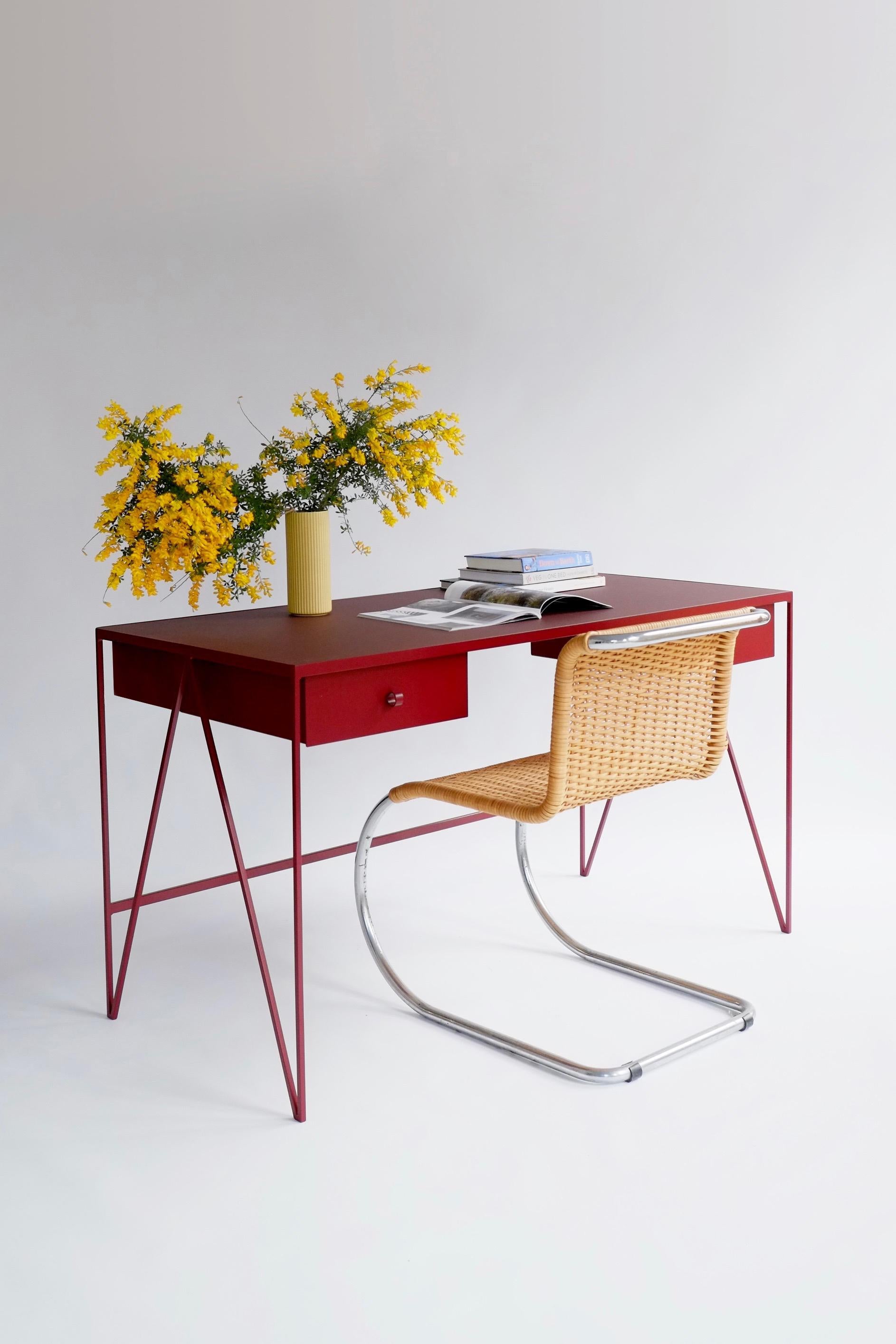 This large beetroot color study desk is made with a powder coated steel frame and a beautiful natural linoleum top made out of linseed oil. This modern minimal desk has two steel drawers suspended underneath the tabletop with our Loop handles. The