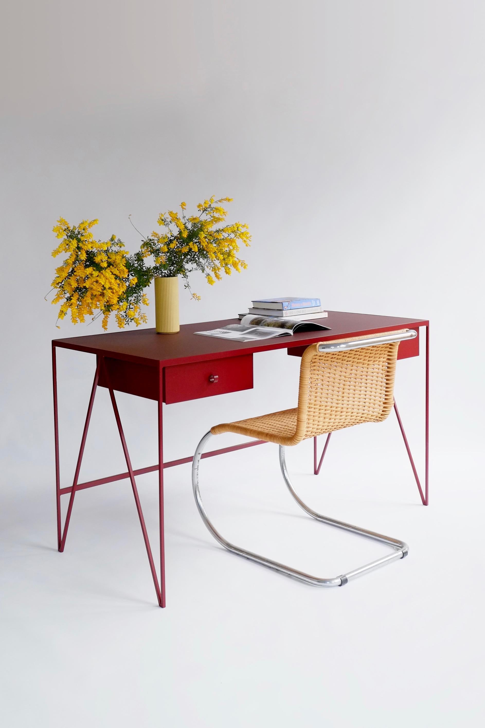 This large beetroot color study desk is made with a powder coated steel frame and a beautiful natural linoleum top made out of linseed oil. This modern minimal desk has two steel drawers suspended underneath the tabletop with our Loop handles. The