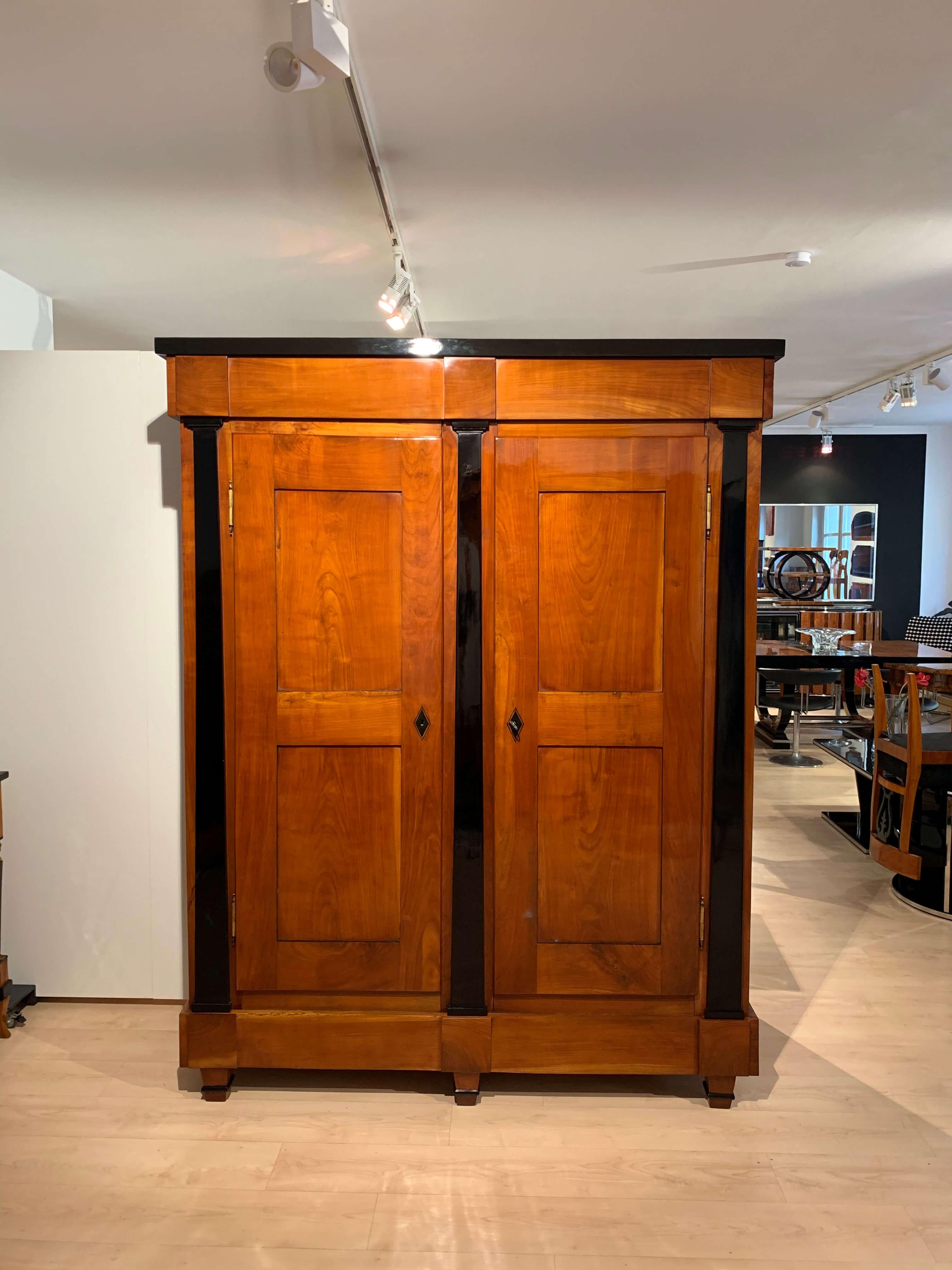 Elegant, large neoclassical, restored early Biedermeier Armoire from Southwest Germany around 1820.

Solid cherry tree, hand polished with shellac (French polished) and partly ebonized. Each two fillings on one door and side.
Three ebonized,