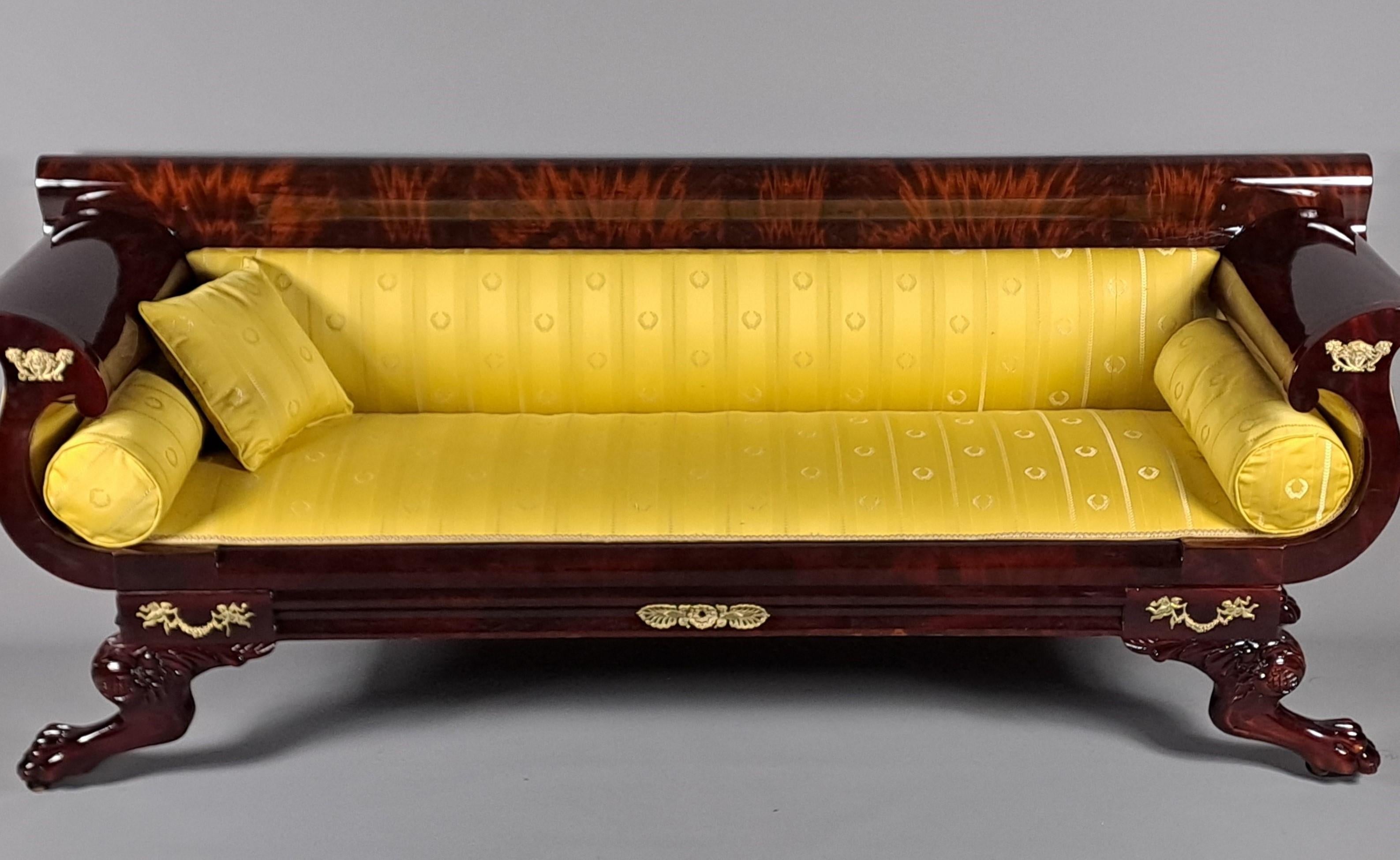 Gran sofá o banqueta de estilo Biedermeier en chapa de caoba burlada y caoba maciza revestida con un hermoso tejido imperio clásico en oro viejo con motivos de coronas de laurel.

Hermosa ornamentación de bronce cincelado y dorado.

Cuatro patas de