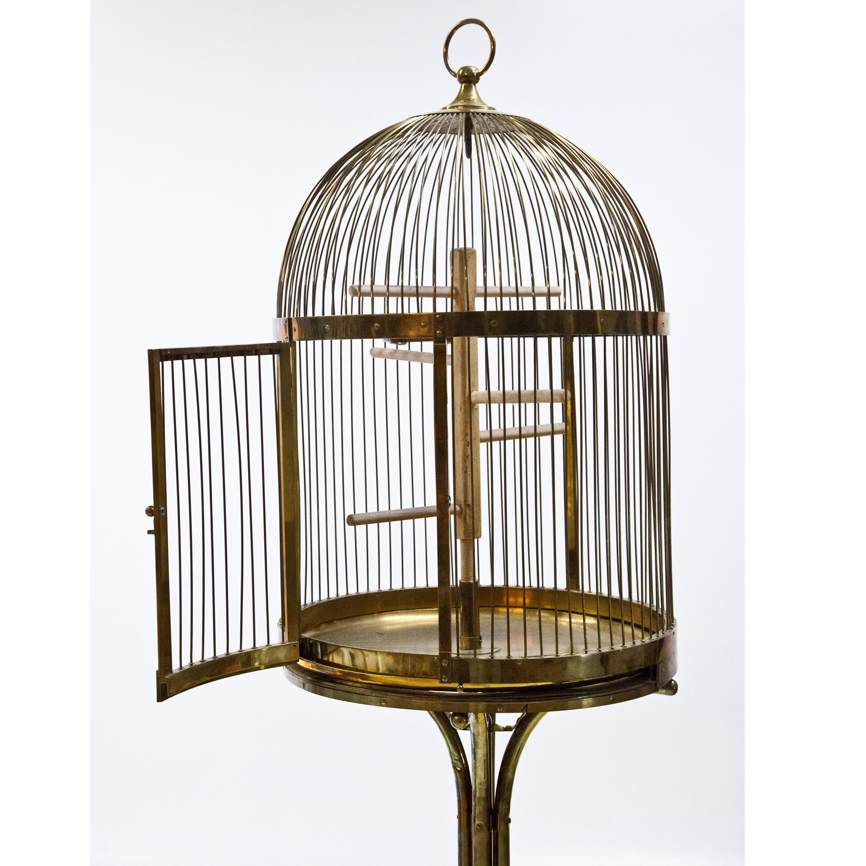 Large brass bird cage on four-legged stand with round base and vertical struts. A similar piece of the same collection was stamped 