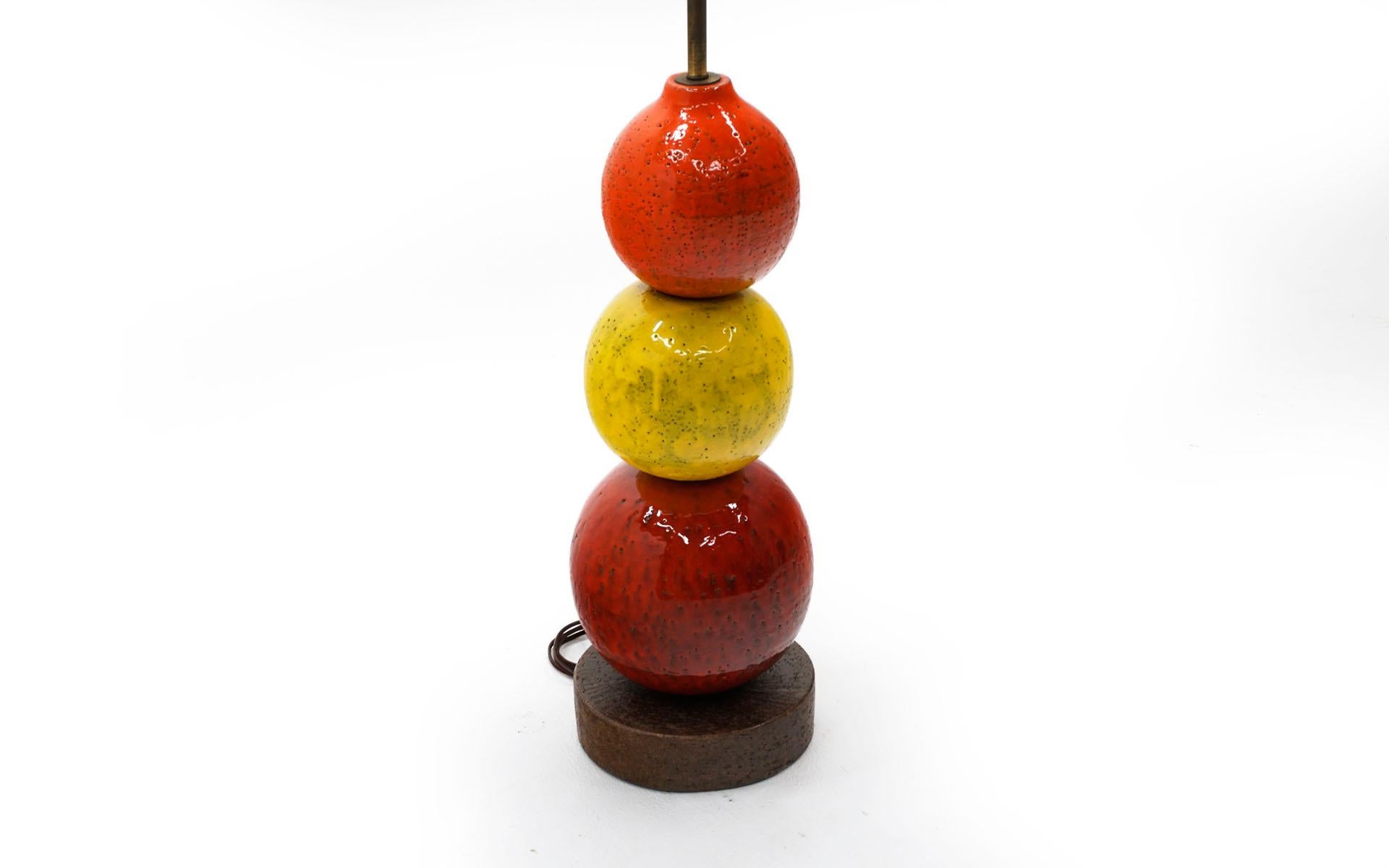 Pottery ball table lamp by Bitossi, Italy, 1960s in red, yellow and orange. Free of chips or scratches, this was acquired from the original owners. Retains its original finial. Lamp is sold without a shade.