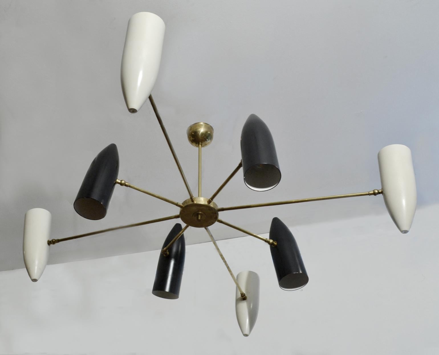 Up and down lighter chandelier with eight black and white adjustable concentric metal shades with alternating lengths radiating from a eight arms brass tubular frame and connected by a brass central cylinder cup.
Excellent statement as a