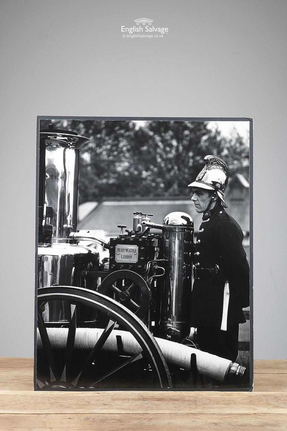 Good sized black and white photo of a fireman stood by a vintage Merryweather London fire engine. Mounted on a black card, would look lovely displayed on its own or in a group. Few minor areas of wear to the corners.