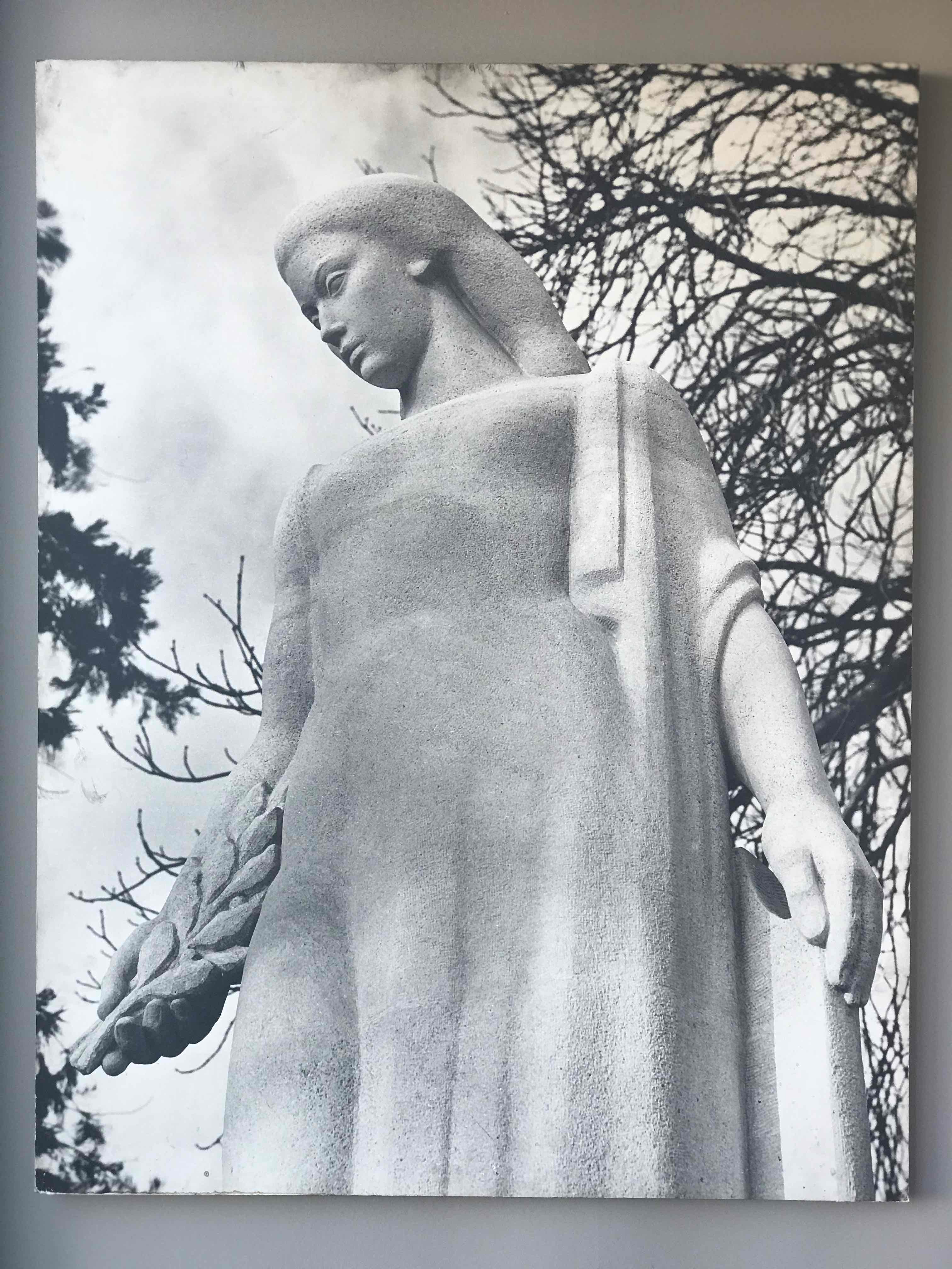 Large black and white photograph of female sculpture.