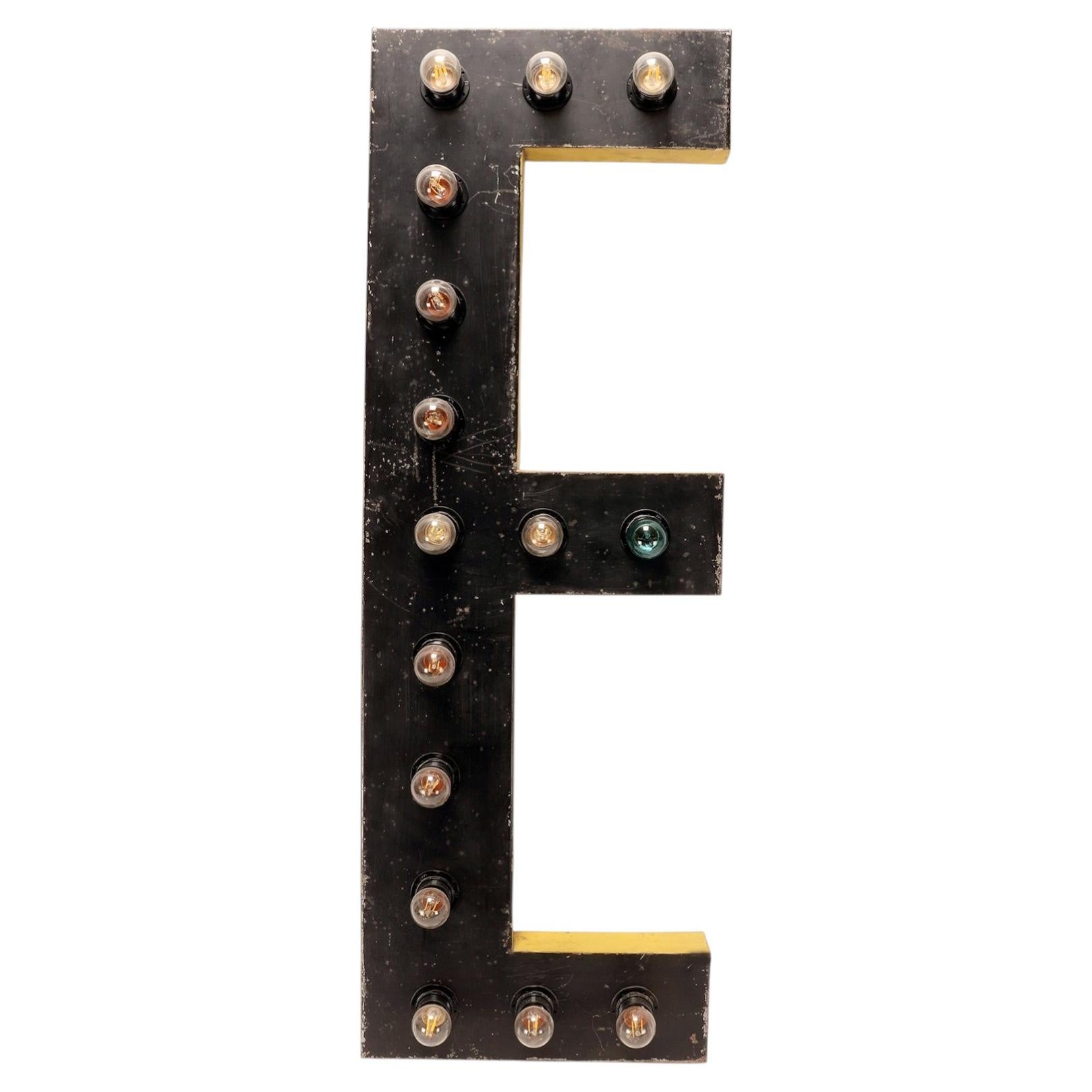 Large black and yellow tin letter E illuminated by light bulbs. USA 1930. For Sale