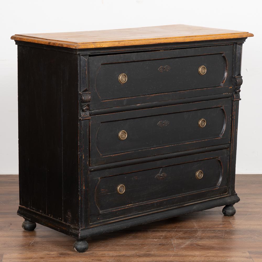 This large pine chest of three drawers has been given new life with a professional black matte painted finish, lightly distressed bringing out the carved details and complimenting the age of the dresser.
The top has been left natural pine creating
