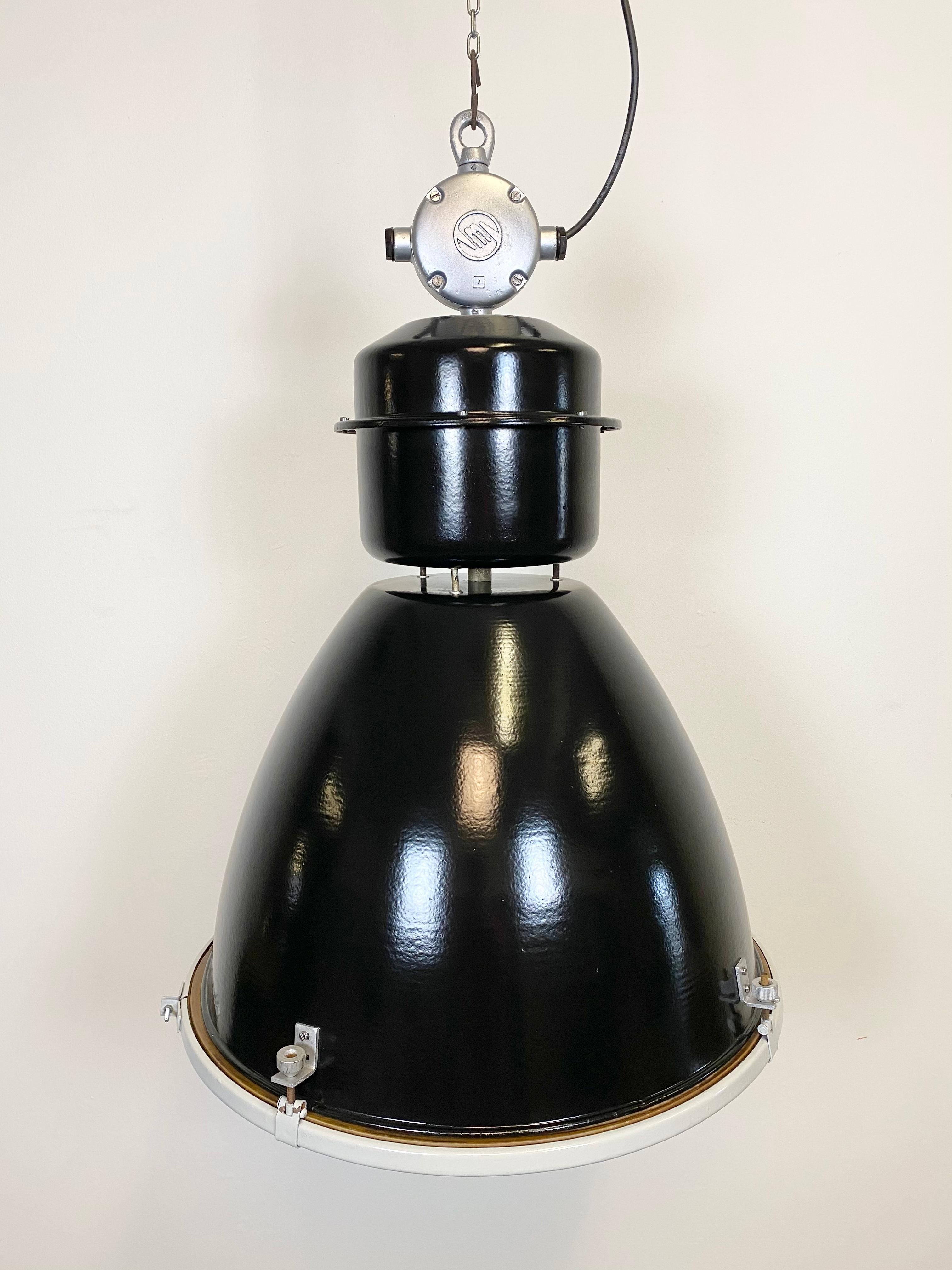 This black industrial pendant light was designed in the 1960s and produced by Elektrosvit in the former Czechoslovakia. It features a cast aluminium top, a black exterior, a white enamel interior and clear glass cover.
New porcelain socket for E 27