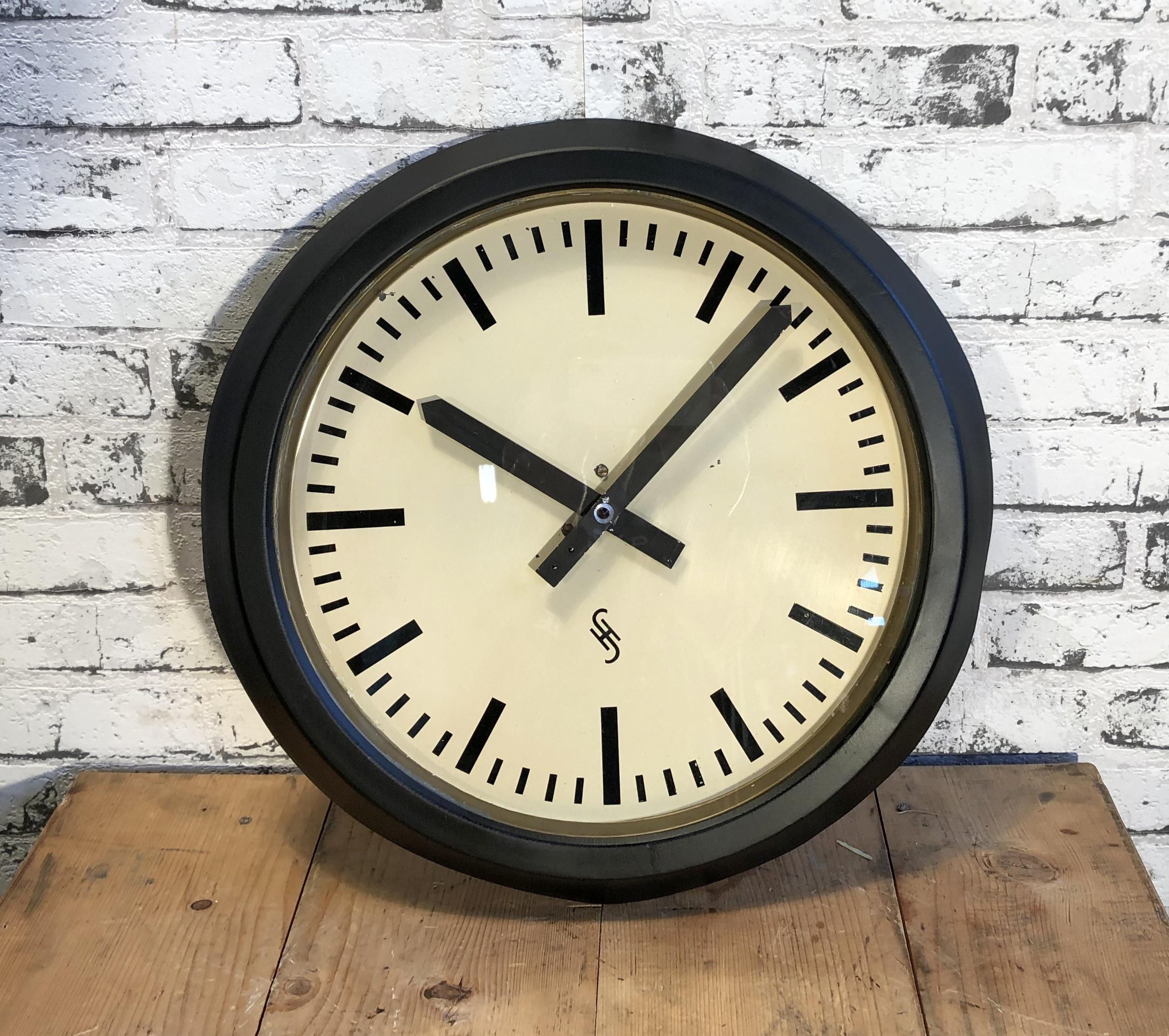 This large wall clock was produced by Siemens and Halske in Germany during the 1950s. It features a black metal frame, aluminum dial, and a clear glass cover. The piece has been converted into a battery-powered clockwork and requires only one