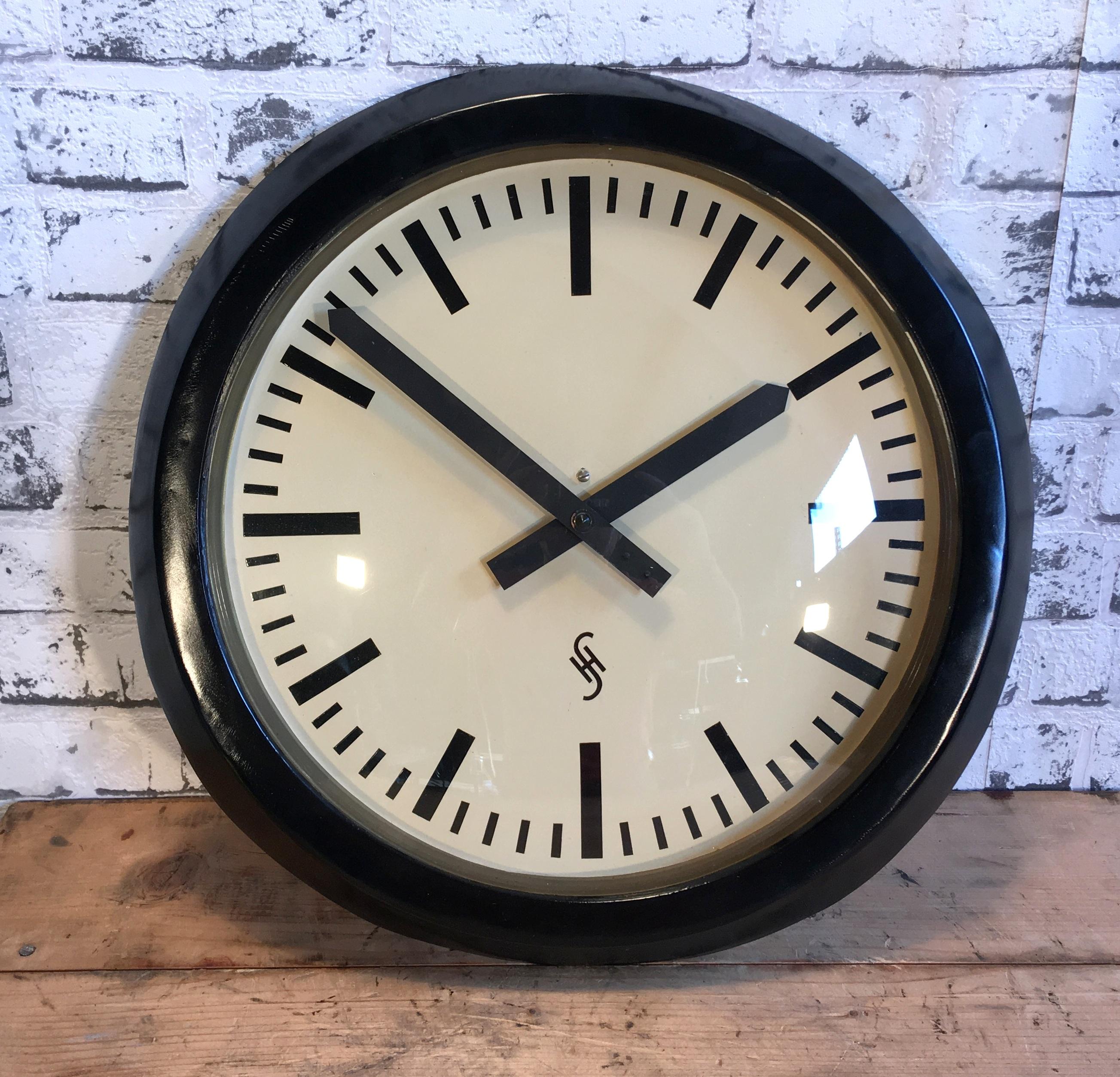 This large wall clock was produced by Siemens Halske in Germany during the 1950s.It features a black metal frame, aluminium dial and clear curved glass cover. The piece has been converted into a battery-powered clockwork and requires only one