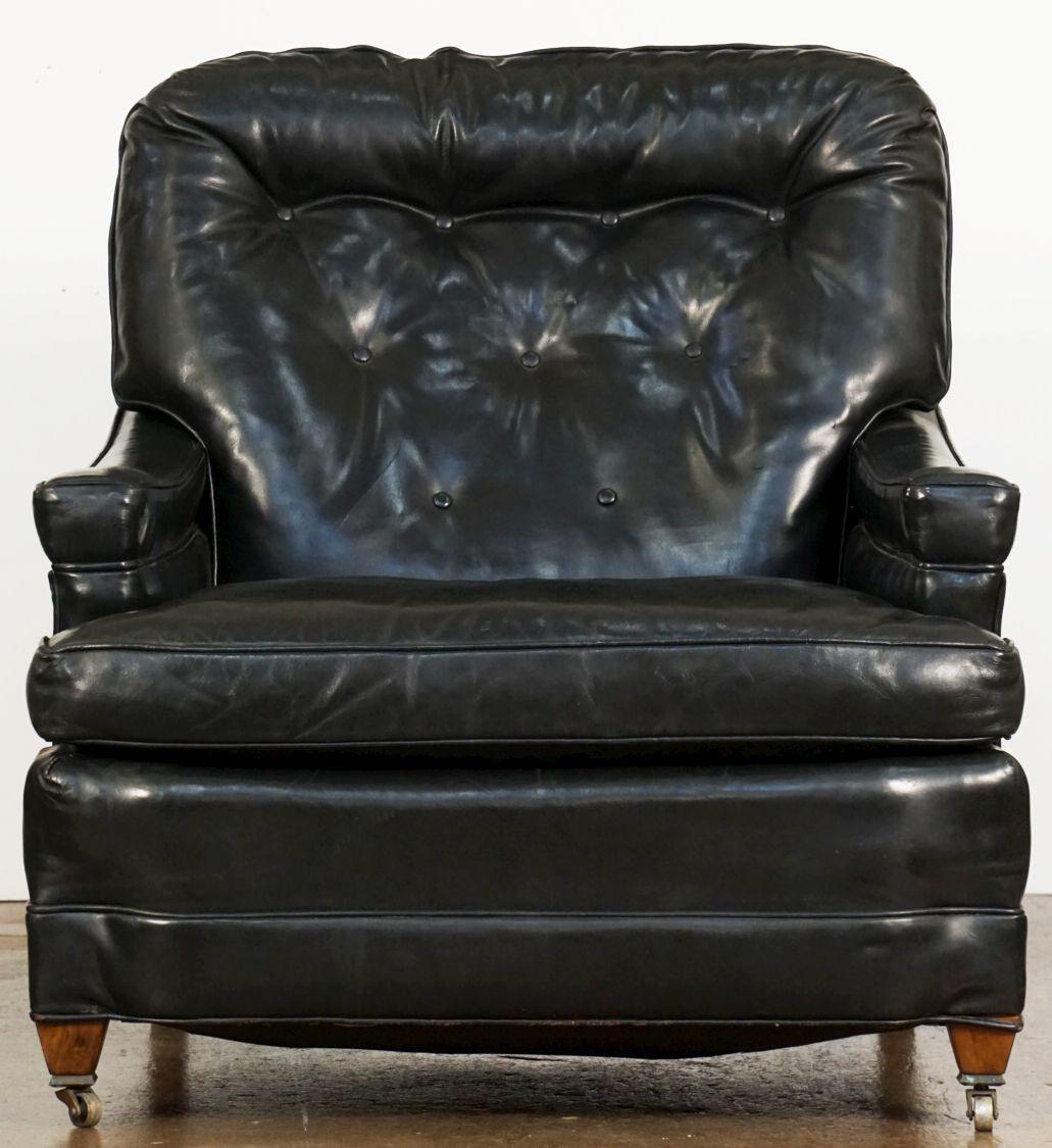 A fine large comfortable upholstered lounge or club armchair by Bloomingdales - New York, with original black leather in very good condition - featuring a tufted back with sway arms, removable fitted seat cushion, and resting on two front-facing